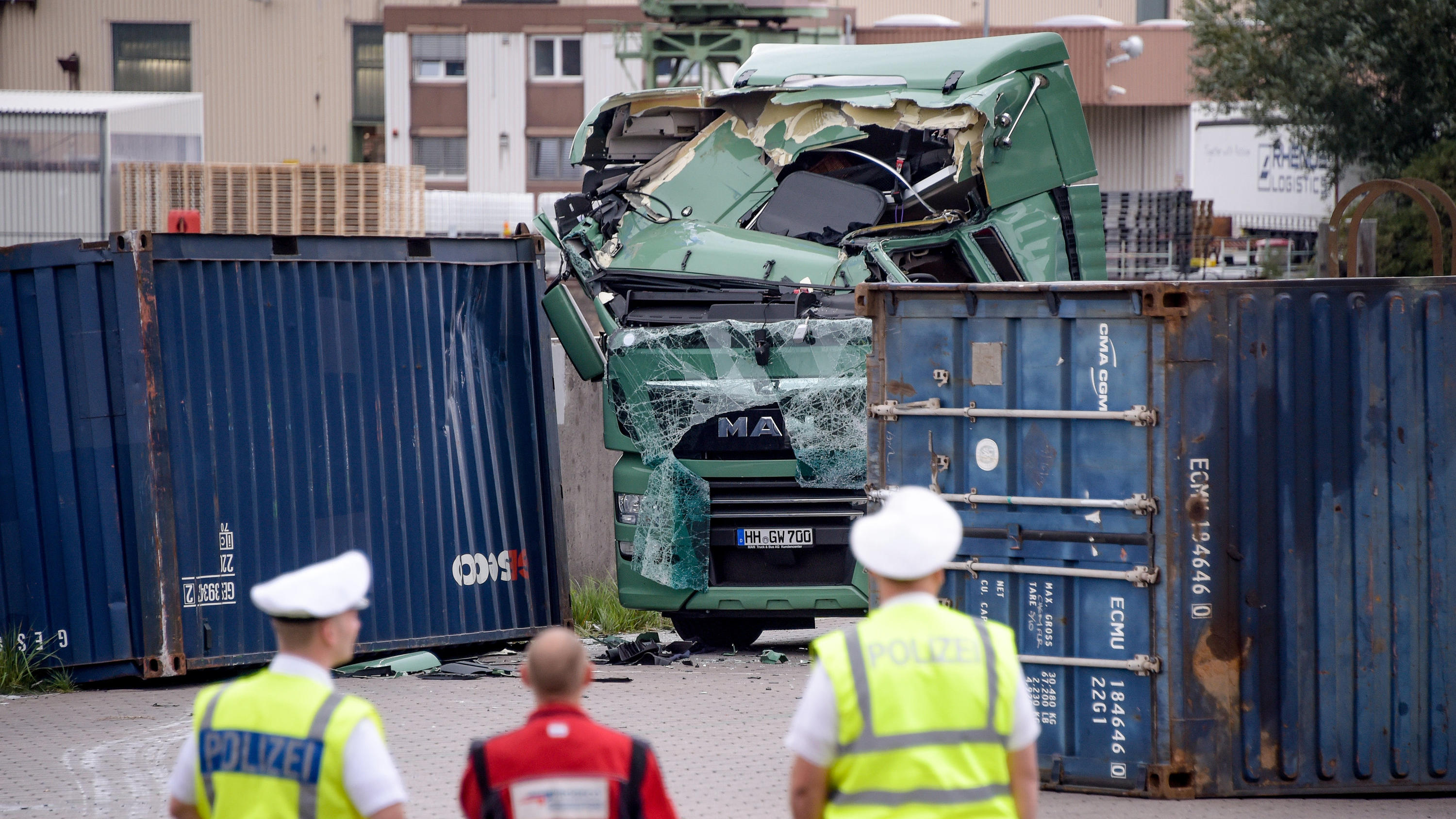 Erster Herbststurm des Jahres schüttelt den Norden richtig durch 21.09.2018, Hamburg: Polizisten und ein Sachverständiger schauen auf einen völlig zerstörten LKW im Hamburger Hafen. Ein Container war durch den starken Sturm auf den LKW gestürzt. Foto: Axel Heimken/dpa +++ dpa-Bildfunk +++