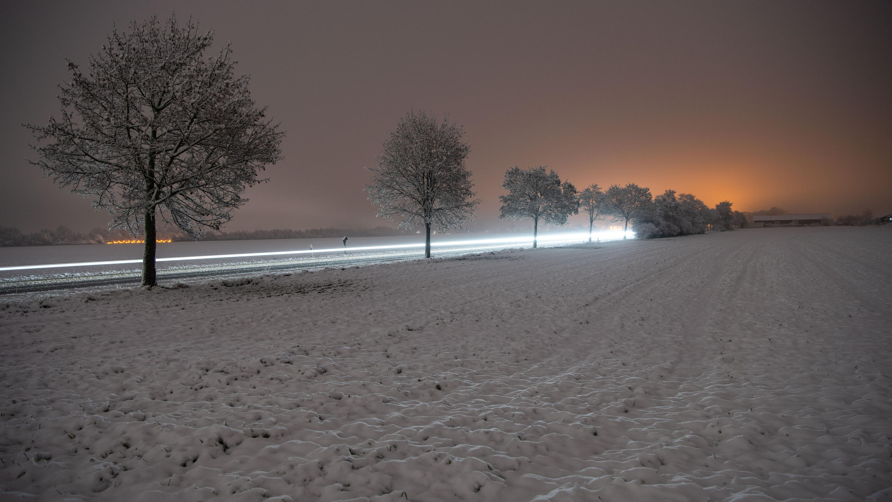 Erster Schnee im Süden Deutschlands: Nässe kann gefährliche Glätte bilden 27.11.2018, Bayern, Vaterstetten: Autos fahren auf einer Landstraße. (Aufnahme mit Langzeitbelichtung) Foto: Lino Mirgeler/dpa +++ dpa-Bildfunk +++