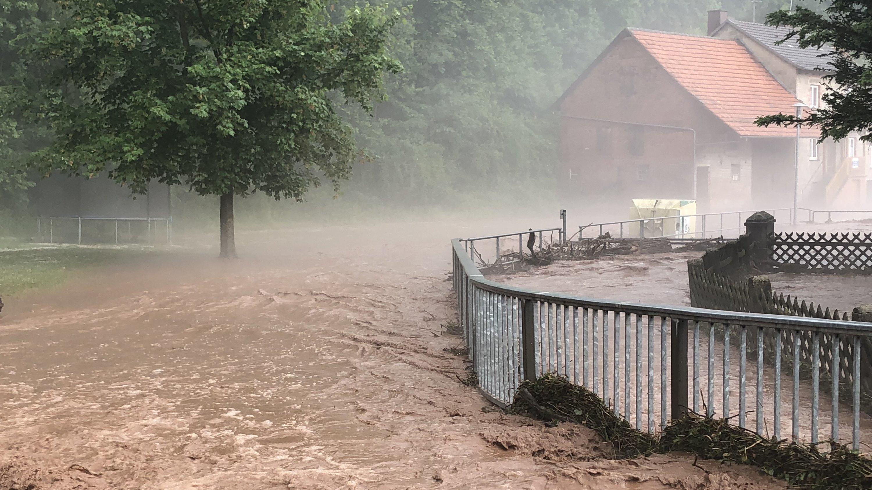 UN-Klimakonferenz in Kattowitz: Verheerende Folgen, wenn wir die 1,5 Grad Erwärmung verfehlen ARCHIV - 27.05.2018, Hessen, Hetzerode: Nach Starkregen und Hagelschlag ist ein Bach über die Ufer getreten. Feuerwehren und Rettungskräfte sind in der Region im Einsatz und pumpen überflutete Keller leer und räumen Schlammlawinen. Foto: Bernd März/d