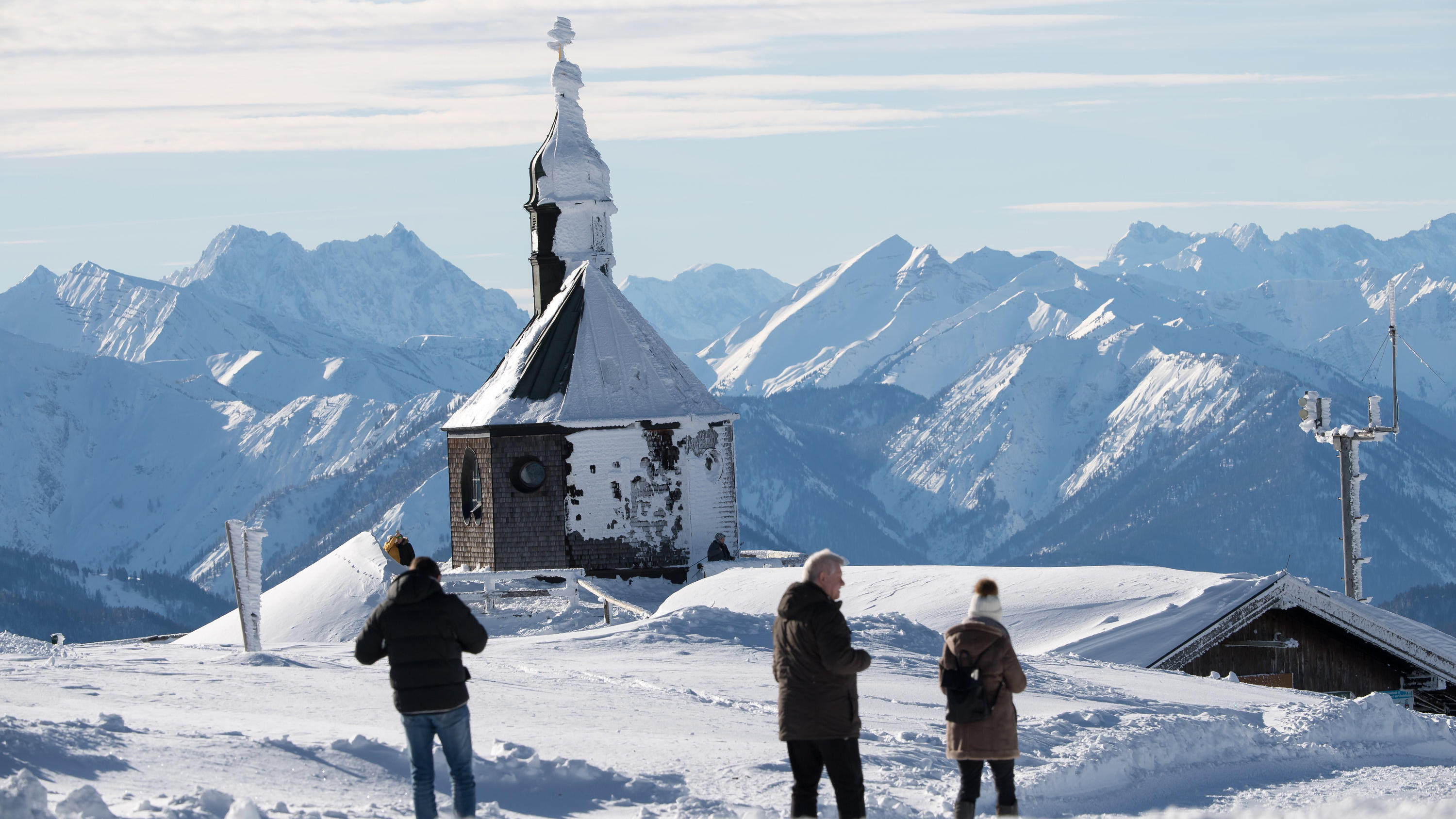 Endlich Sonne am Wochenende: Hochdruck bringt klares, kaltes Wetter 16.01.2019, Bayern, München: Die vom Schnee teilweise bedeckte Wallberg-Kapelle "Heilig Kreuz" steht auf dem Wallberg vor dem Alpenpanorama. Nach Tagelangen heftigen Schneefall im Süden Bayerns scheint über dem Freistaat wieder die Sonne. Foto: Peter