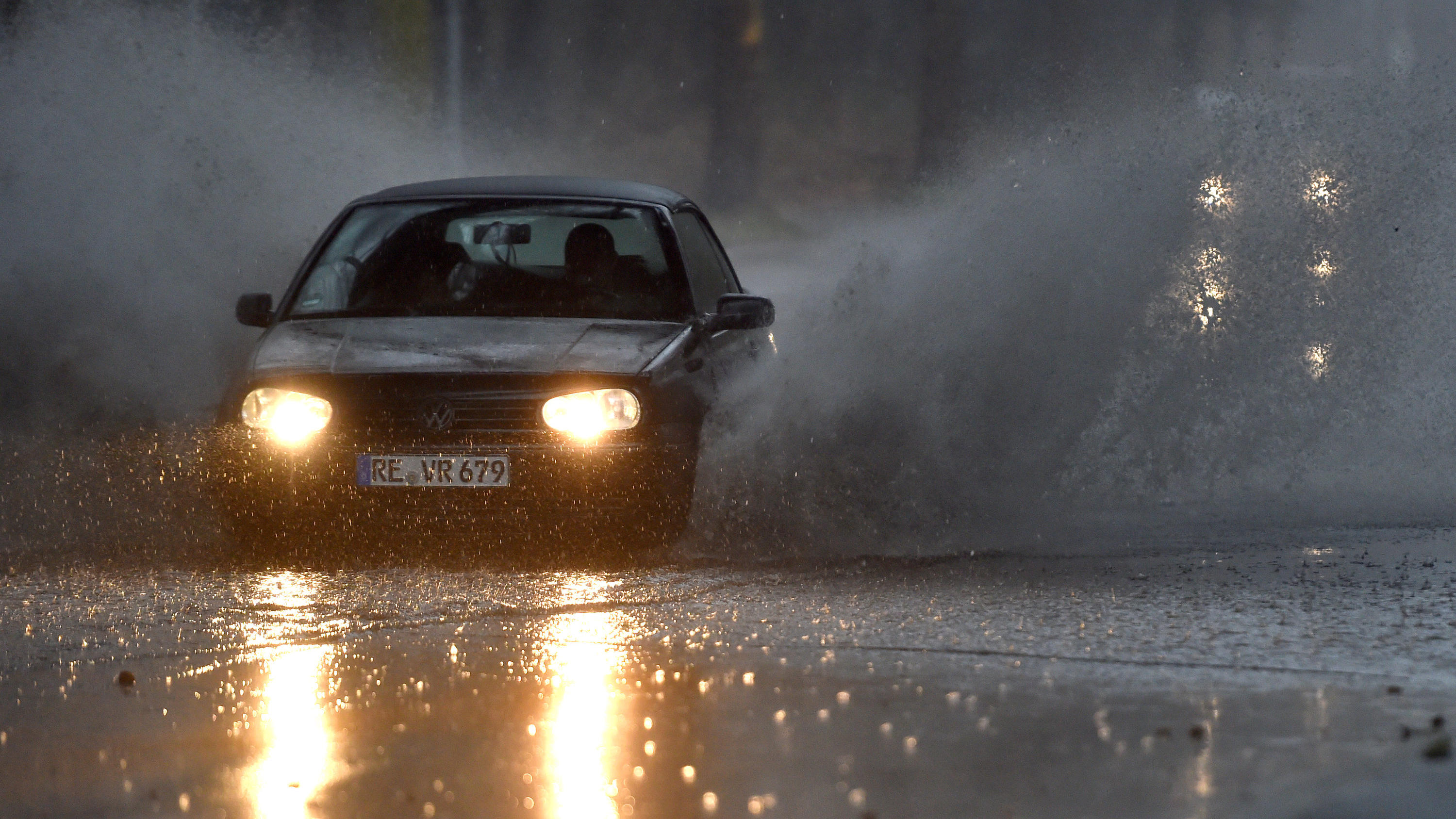 10 Fakten zum Klimawandel: An diesen Stellen ist er jetzt schon messbar 09.03.2019, Nordrhein-Westfalen, Gelsenkirchen: Ein Auto fährt langsam durch eine tiefe Pfütze die sich durch Starkregen auf einer Straße gebildet hat. Mit Sturmböen und Gewitter hat Sturmtief Dragi am Samstagnachmittag in Nordrhein-Westfalen für Pro