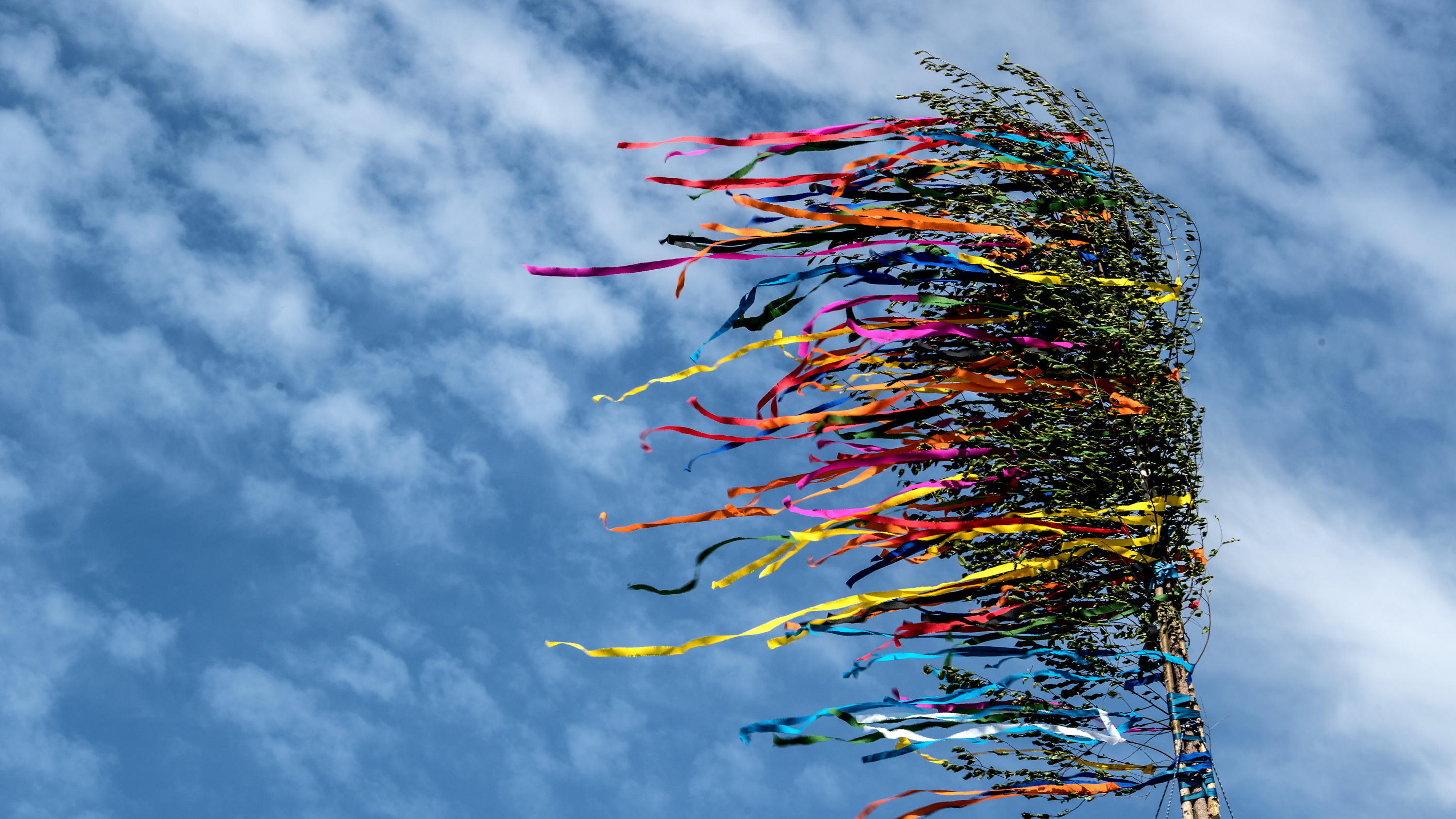 Ungemütliches Wetter: Regen und Gewitter am 1. Mai 2020 Die bunten Bänder eines Maibaumes flattern vor dem blauen Himmel. (zu dpa/lnw: