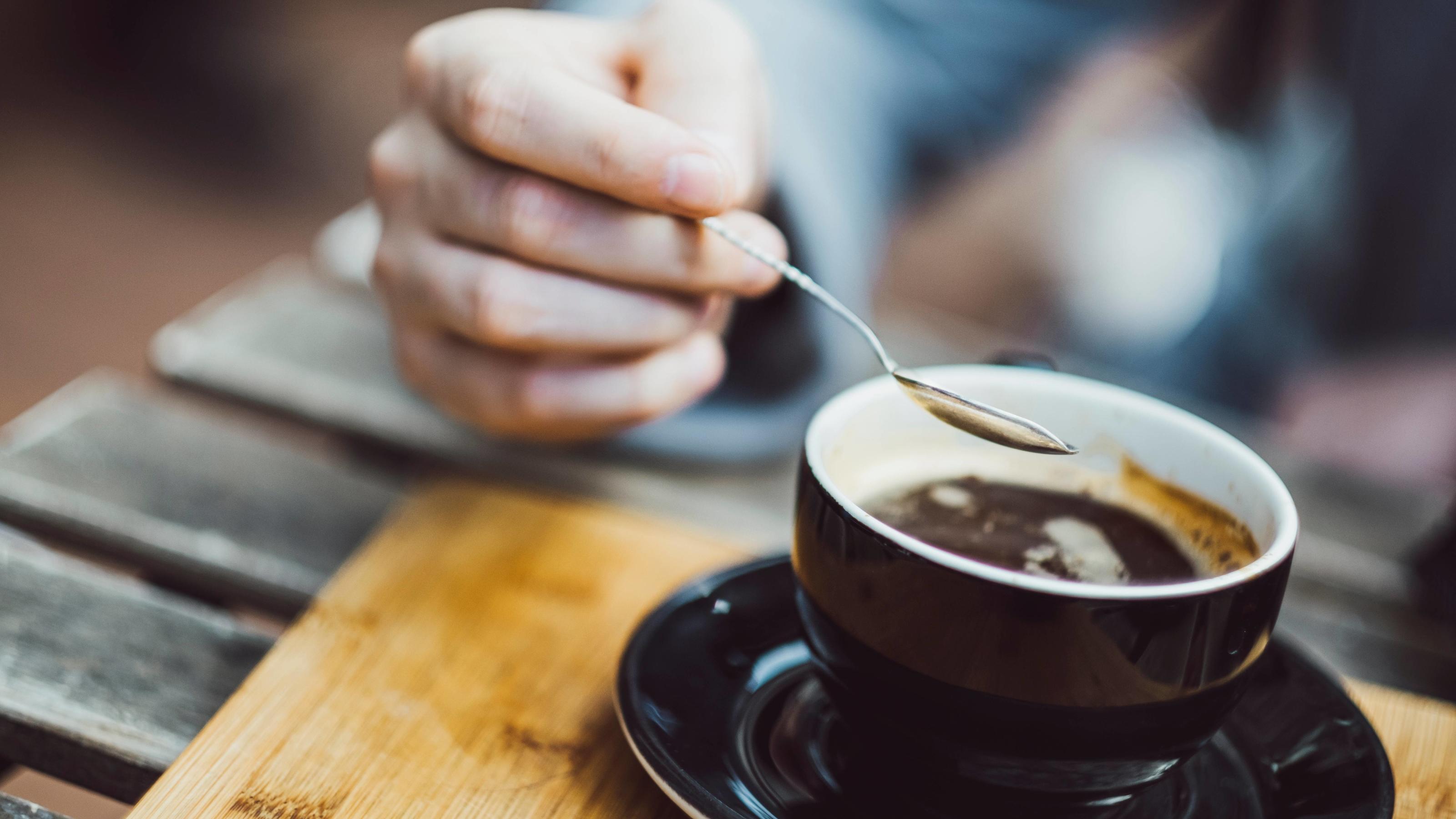 Fünf Wahrheiten über Kaffee Mann rührt mit Löffel im Kaffee ESSEN UND TRINKEN / creative *** Man stirs with spoon in the cafe. EAT AND DRINK creative PUBLICATIONxINxGERxSUIxAUTxONLY Copyright: JonathanxSchöpsx/xPhotocase photocase_2374933