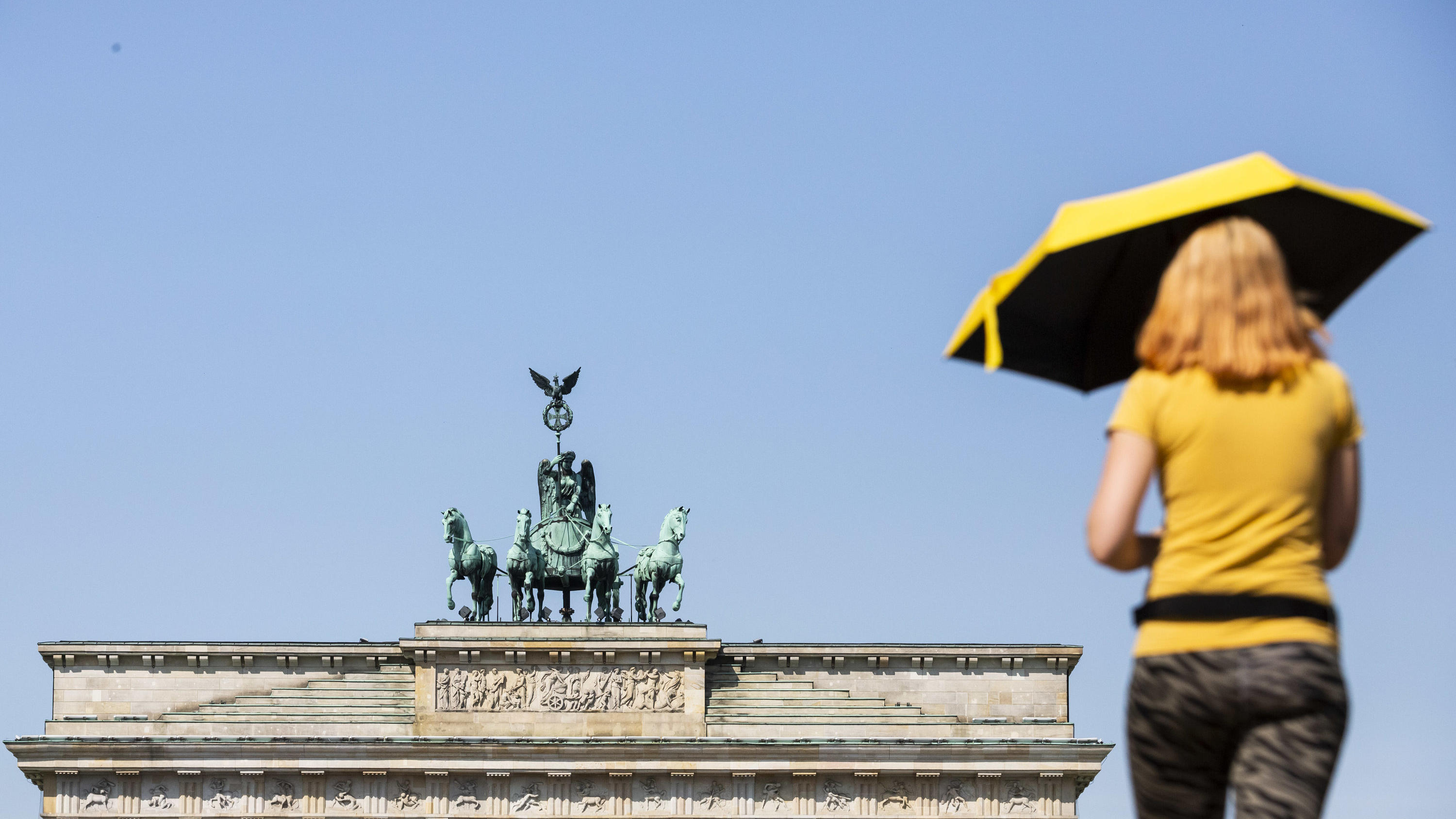 Schafskälte im Juni 2019: Das steckt hinter dem Wetterphänomen dpatopbilder - 04.06.2019, Berlin: Eine Frau mit Sonnenschirm läuft vor dem Brandenburger Tor mit der Quadriga. Foto: Christoph Soeder/dpa +++ dpa-Bildfunk +++