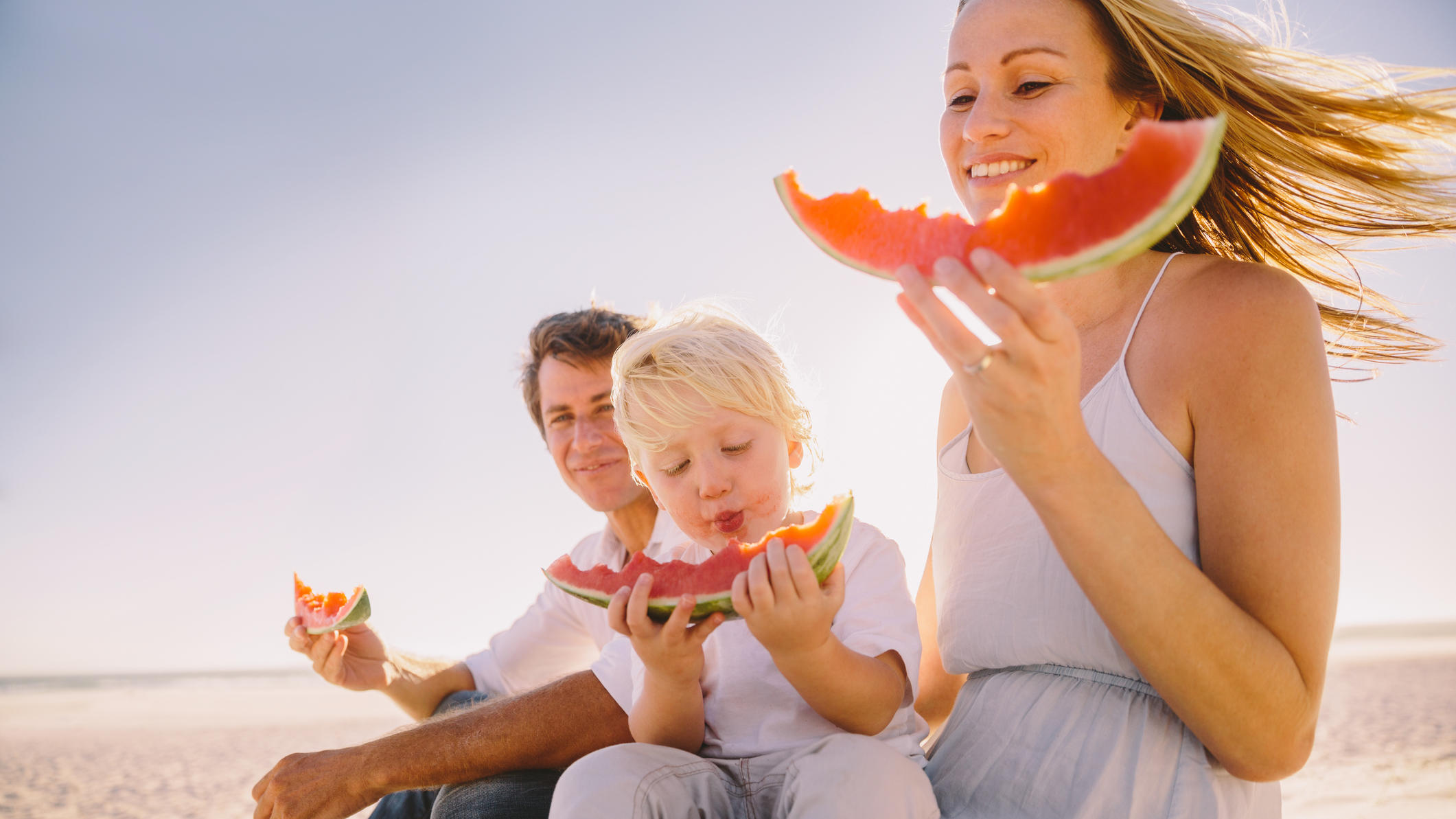 Wie viel sollten wir bei Hitze trinken? Familie isst Wassermelone.