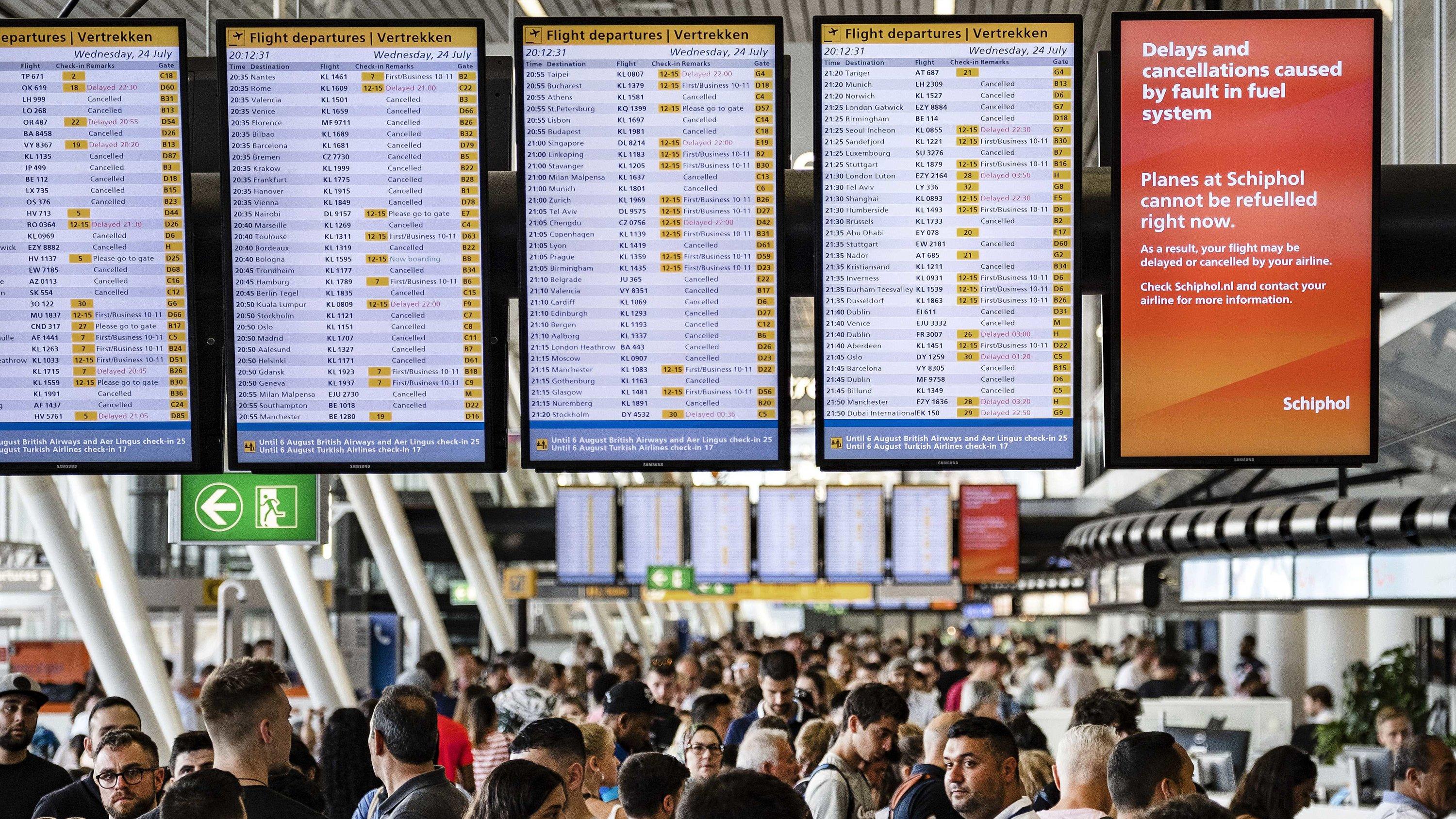 Live-Ticker zum Orkan Sabine: Frau aus dem Main gerettet - Vier Rettungskräfte in NRW verletzt 24.07.2019, Niederlande, Amsterdam: Zahlreiche Fluggäste warten am Flughafen Schiphol unter Anzeigetafeln mit einem Hinweis: