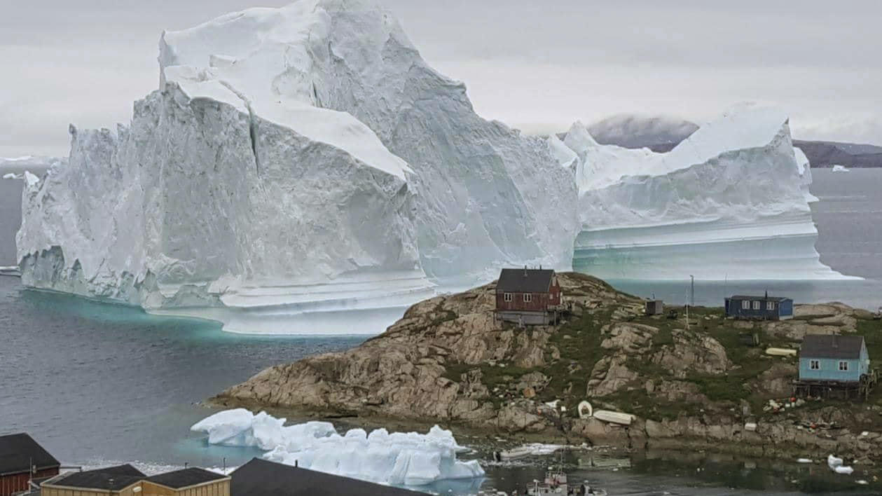 Grönlands Klimawandel in Flaschen: Schwachsinn oder sinnvoll? ARCHIV - 13.07.2018, Grönland, Innaarsuit: Ein Eisberg schwimmt vor der grönländischen Küste am Dorf Innaarsuit vorbei. Politiker in Dänemark haben mit Verwunderung und Kritik auf das angebliche Interesse von US-Präsident Donald Trump an einem Kauf G