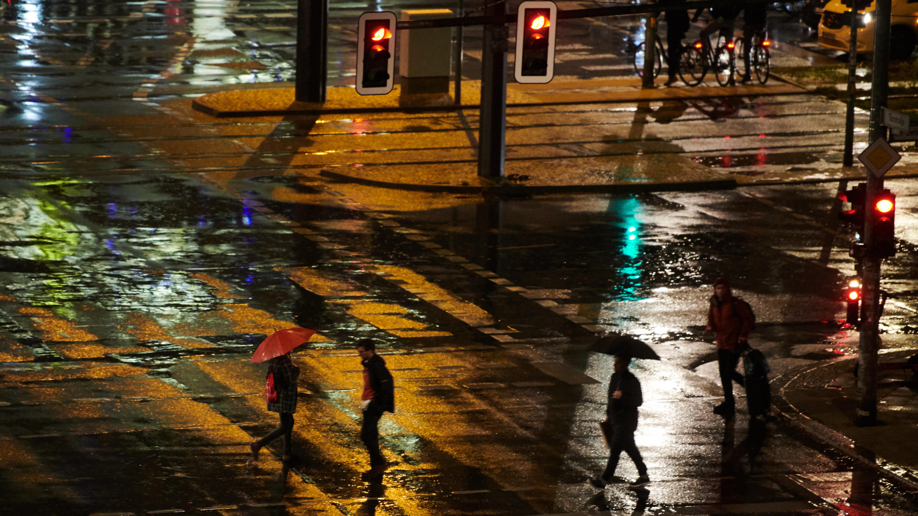 Herbst-Schmuddelwetter: Dauerregen sorgt für Chaos auf Deutschlands Straßen 04.10.2019, Berlin: Menschen mit Regenschirmen gehen über die Ampel. Foto: Annette Riedl/dpa +++ dpa-Bildfunk +++