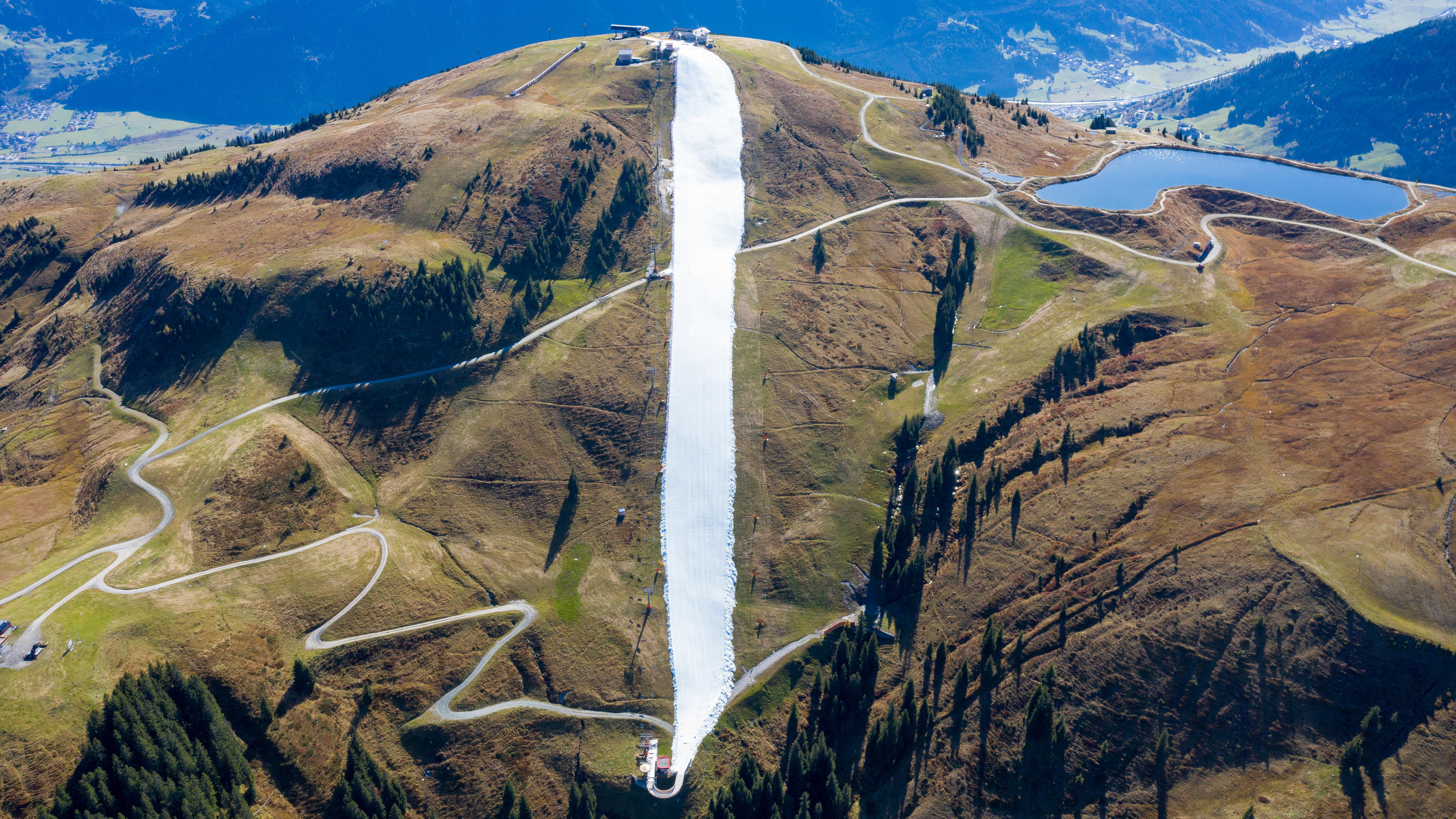 Kitzbühel eröffnet Skisaison mit Altschnee - Jetzt hagelt es Kritik 18.10.2019, Österreich, Mittersill: Für eine schmale Piste wurde konservierter Schnee aus dem vergangenen Winter als Band in der Berglandschaft auf der noch grünen Resterhöhe in den Kitzbüheler Alpen aufgetragen. Die Bergbahnen Kitzbühel gehen das fü