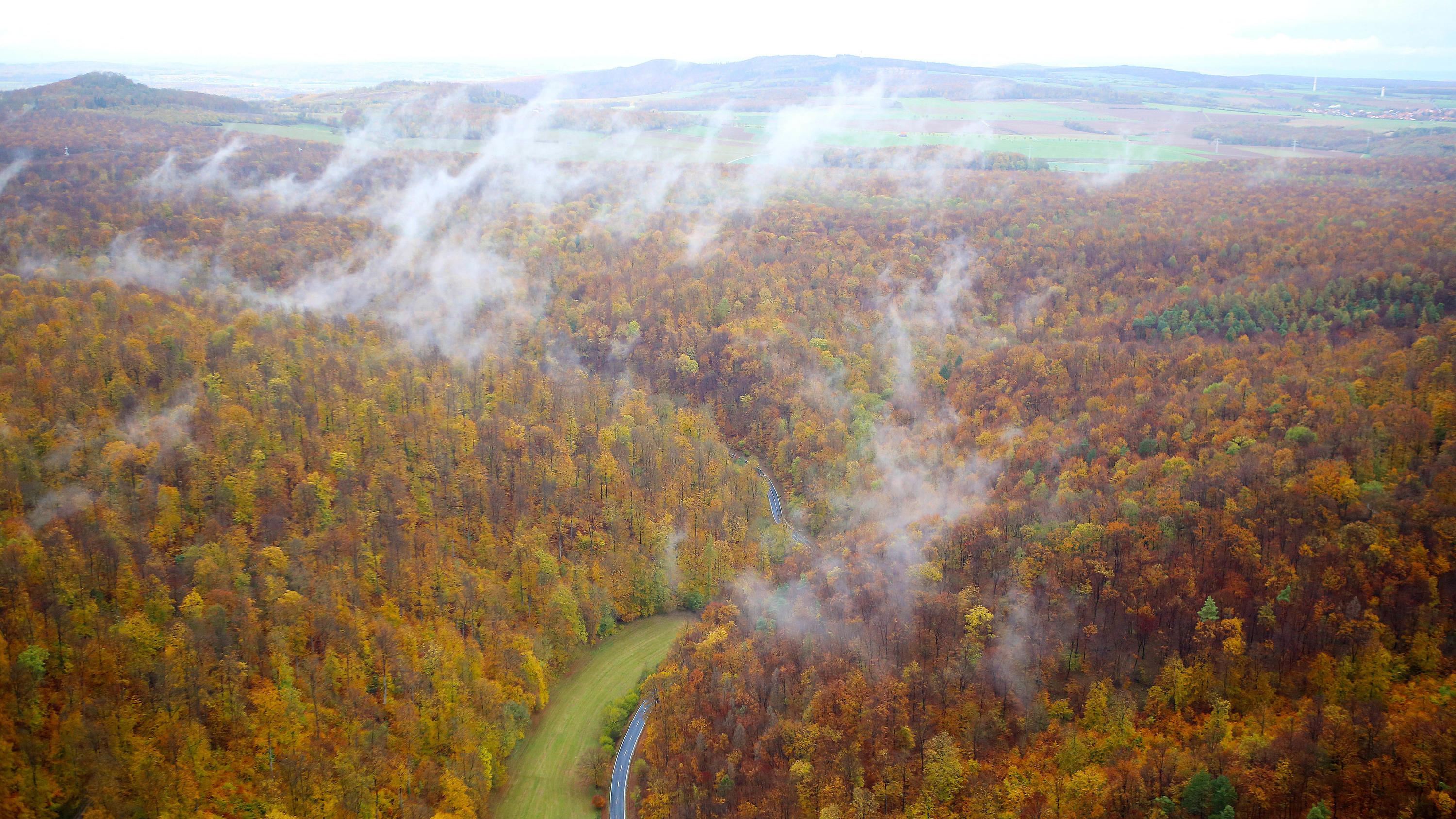 7-Tage-Wettertrend: Das Comeback des Schmuddel-Novembers 05.11.2019, Niedersachsen, Hedemünden: Nebelschwaden steigen nach einem Regenschauer aus einem Laubwald, dessen Blätter herbstlichbunt verfärbt sind. Das Foto ist aus einem Kleinflugzeug aufgenommen. Foto: Stefan Rampfel/dpa +++ dpa-Bildfunk +++