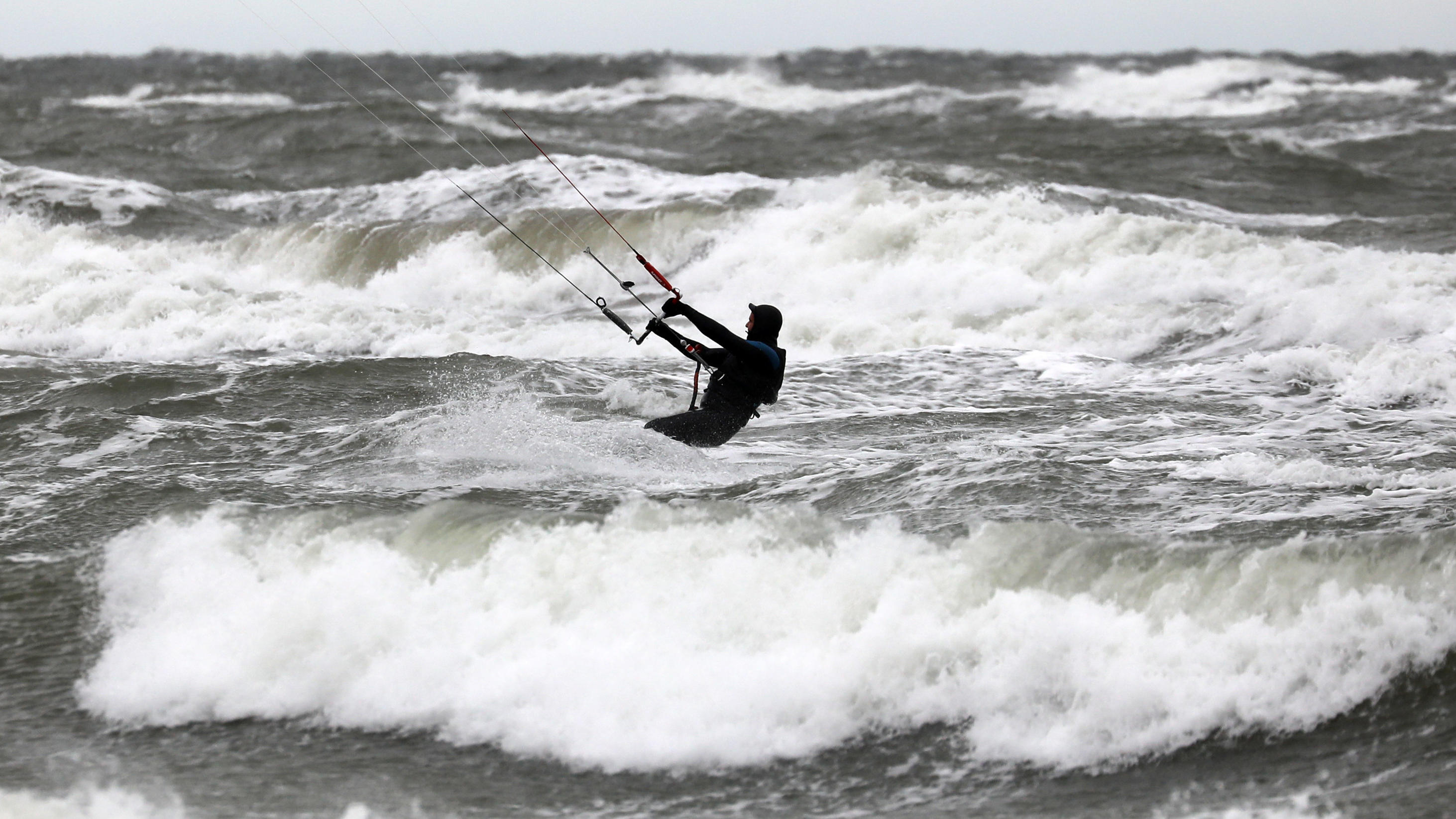 7-Tage-Wettertrend: Die Schneefallgrenze sinkt 29.11.2019, Mecklenburg-Vorpommern, Rostock: Ein Kite-Surfer nutzt den stürmischen Wind über der aufgewühlten Ostsee in Warnemünde für seinen Sport. Die Sturmböen erreichen Stärken von 8-9. Foto: Bernd Wüstneck/dpa-Zentralbild/dpa +++ dpa-Bildfunk ++