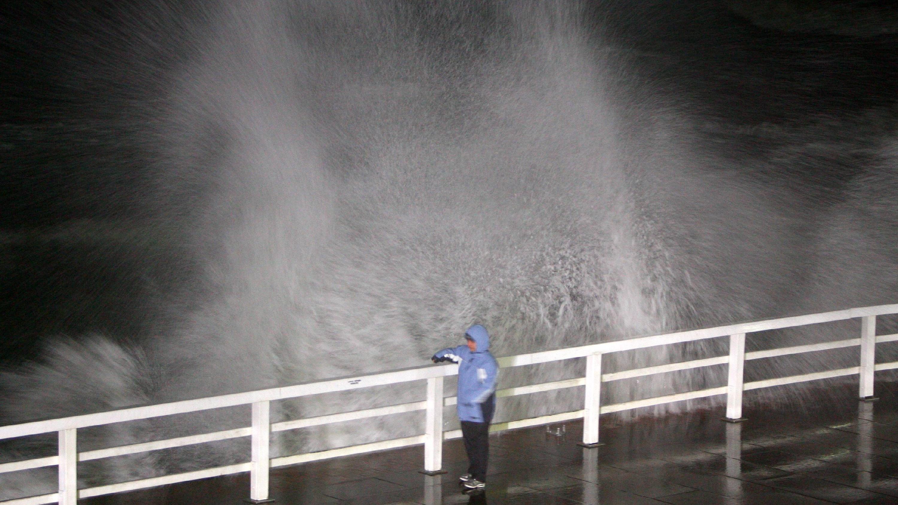 Die schlimmsten Wetter-Kapriolen im Januar Eine Frau geht am frühen Freitagmorgen (19.01.2007) in Westerland auf Sylt über die Promenade während die Brandung gegen die Uferböschung schlägt. Das Orkantief