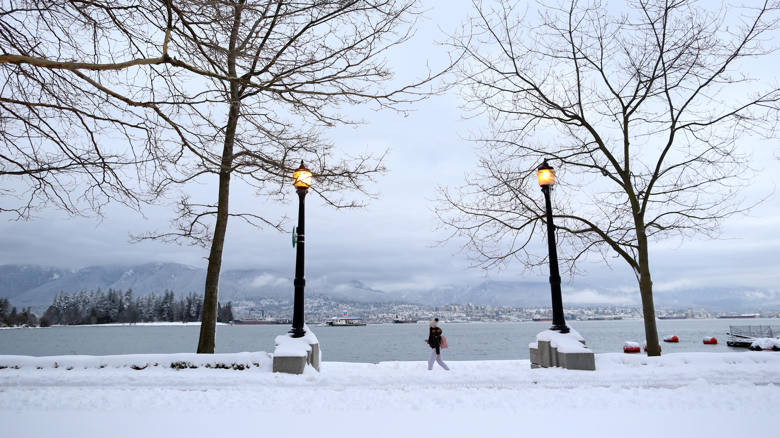 Arktischer Winter fällt über Nordamerika herein A woman walks along the seawall near Coal Harbour, with North Vancouver in the background, after a snow storm in downtown Vancouver, British Columbia, Canada January 15, 2020. REUTERS/Jesse Winter