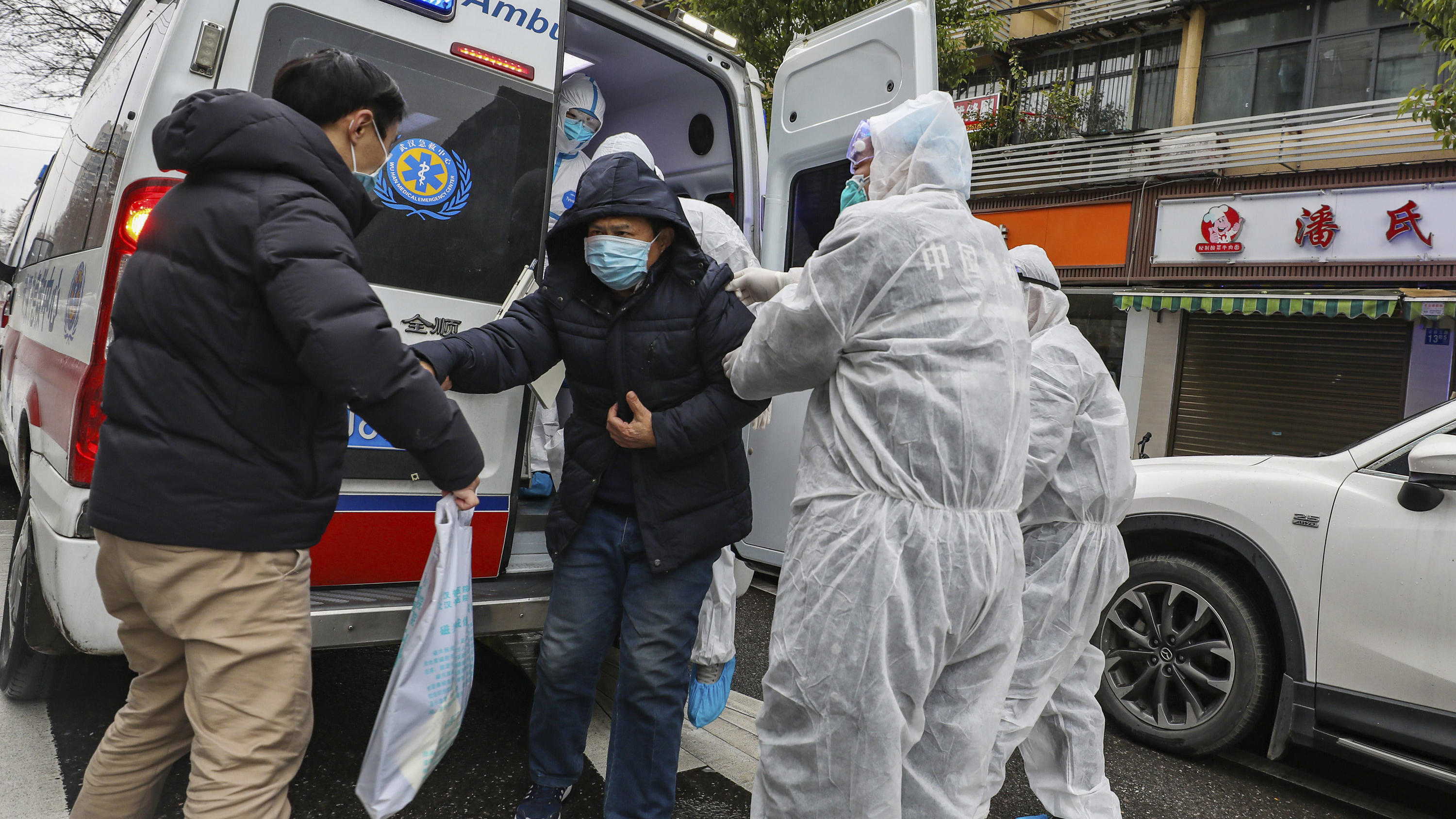 Coronavirus-Chronik Teil 1 26.01.2020, China, Wuhan: Krankenhausmitarbeiter in Schutzkleidung helfen einem Patienten aus einem Krankenwagen. Angesichts der starken Ausbreitung der neuen Lungenkrankheit hat China seine Maßnahmen am Wochenende deutlich verschärft. Foto: Uncredit