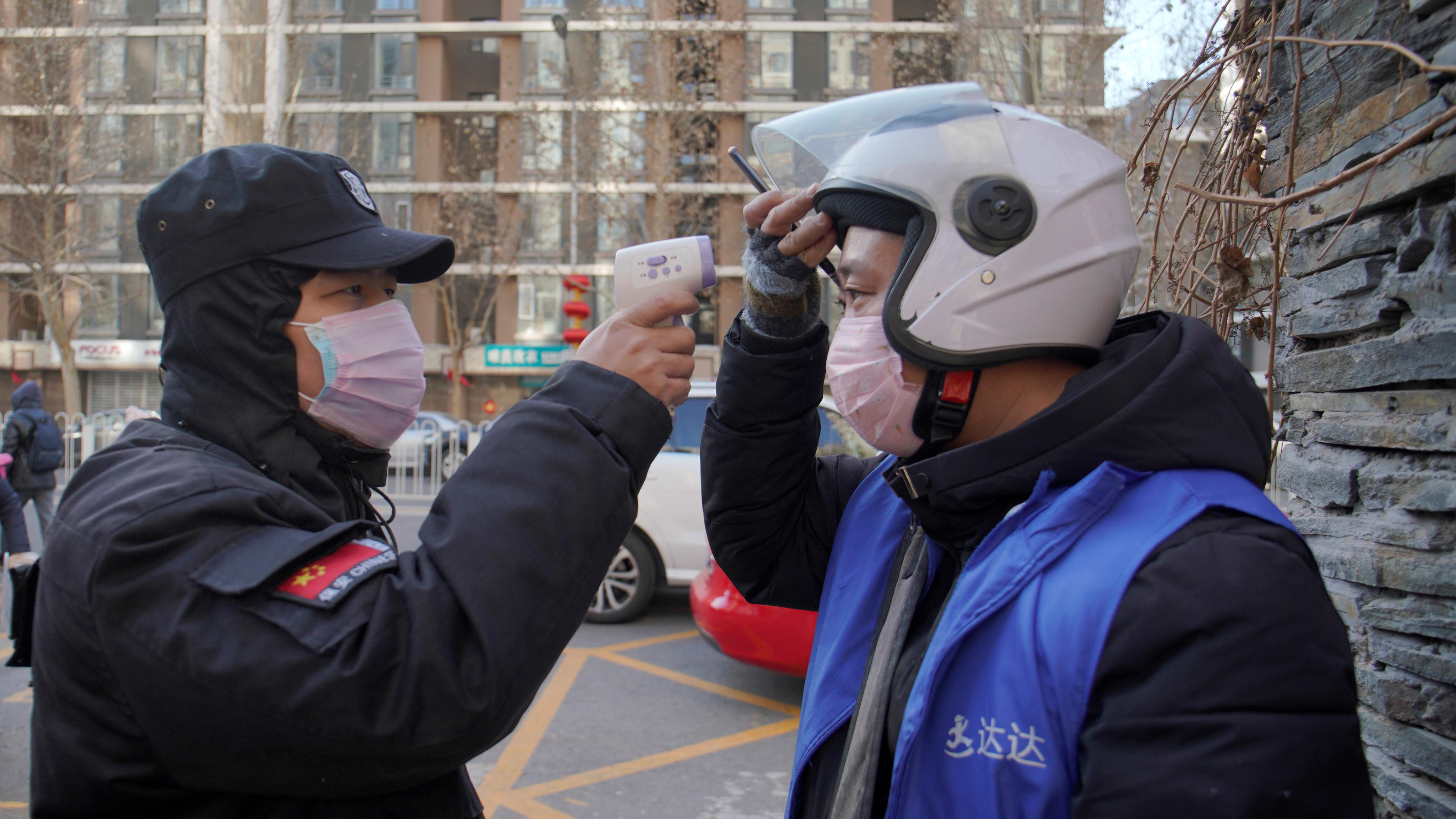 Coronavirus-Chronik Teil 1 A security officer takes body temperature measurement of a delivery worker at a residential compound in Beijing, China as the country is hit by an outbreak of the new coronavirus, February 1, 2020. REUTERS/Stringer NO RESALES. NO ARCHIVES.