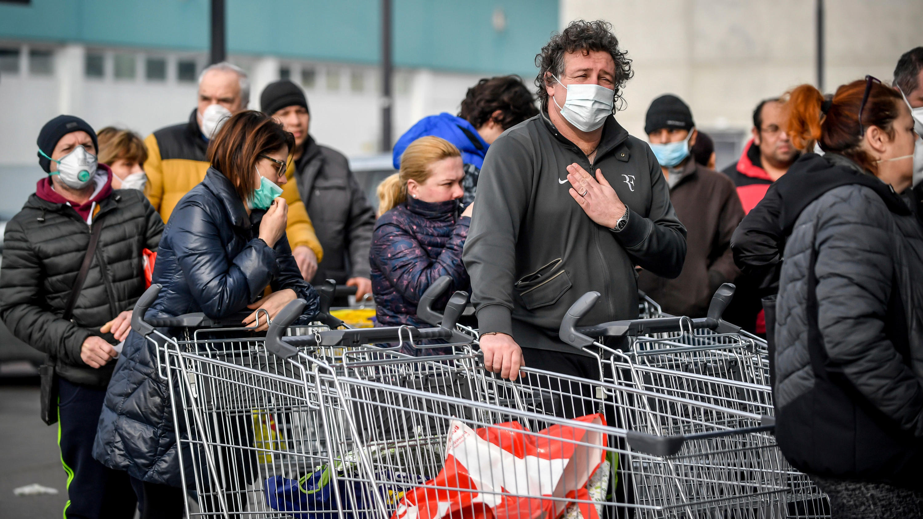 Coronavirus aus China: Chronik der bisherigen Ausbreitung - Teil 5 dpatopbilder - 23.02.2020, Italien, Casalpusterlengo: Menschen tragen Atemschutzmasken und stehen vor einem Supermarkt in einer Schlange. Nach dem Tod zweier Menschen sind Teile des öffentlichen Lebens zum Erliegen gekommen. Kein europäisches Land ha