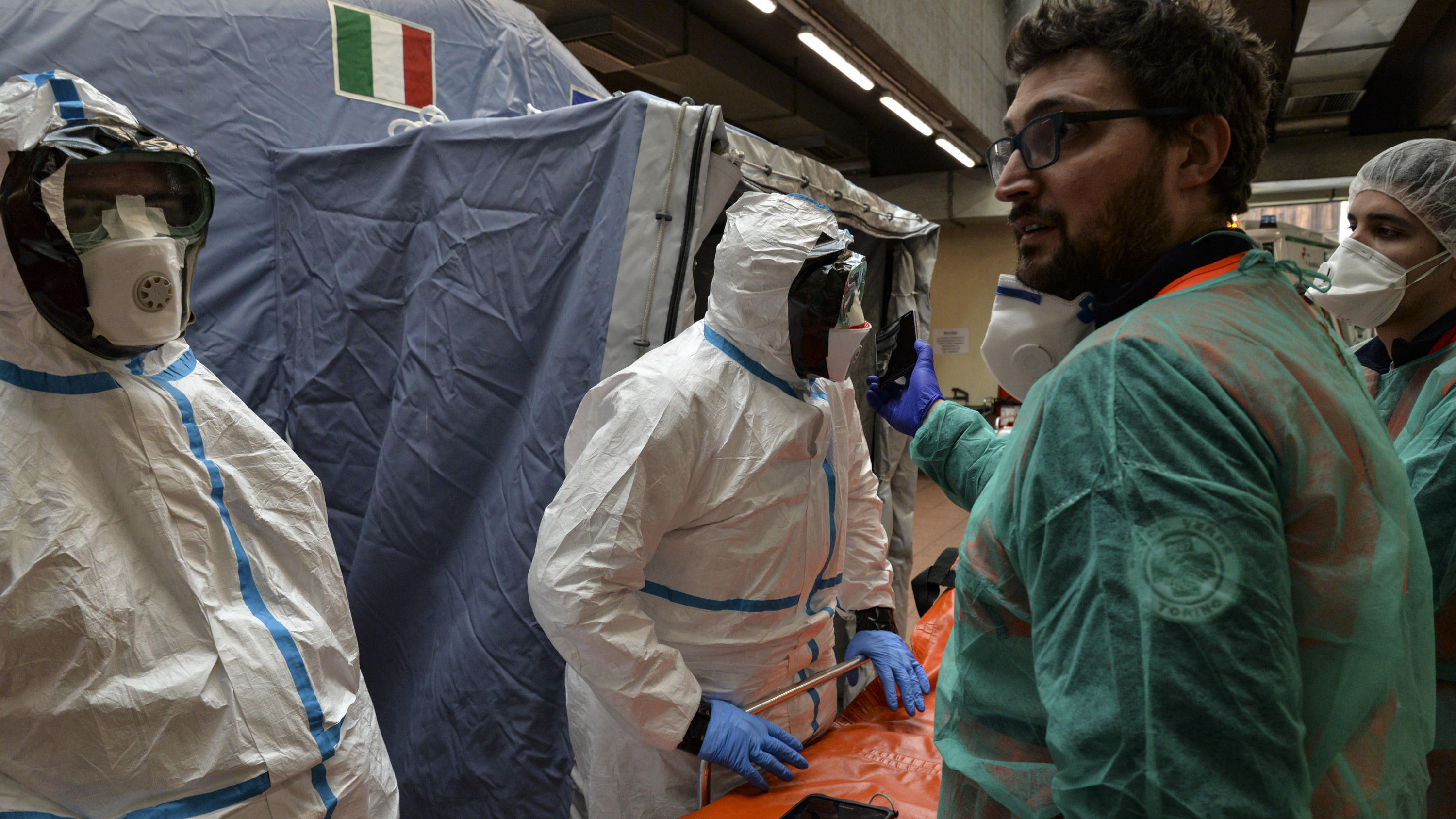 Coronavirus aus China: Chronik der bisherigen Ausbreitung - Teil 5 25.02.2020, Italien, Turin: Mitarbeiter in Schutzanzügen stehen in einem Krankenhaus neben einer Liege. Bei dem neuen Coronavirus steigt in Italien die Zahl der Toten und Infizierten weiter an. Foto: Diego Puletto/SOPA Images via ZUMA Wire/dpa +++ dp