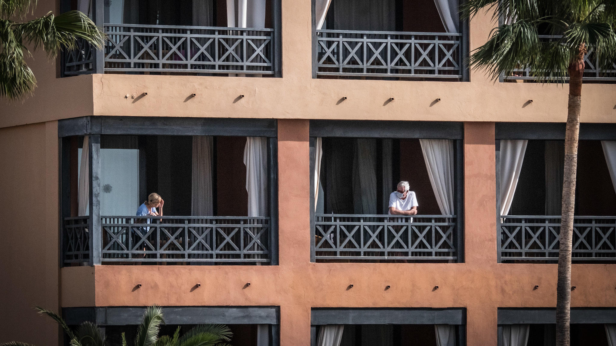Coronavirus aus China: Chronik der bisherigen Ausbreitung - Teil 5 27.02.2020, Spanien, Santa Cruz de Tenerife: Das Hotel H10 Costa Adeje Palace, auf dessen Balkon Gäste stehen. Das wegen Coronavirus-Fällen unter Quarantäne gestellte Hotel auf Teneriffa ist weiterhin durch die Polizei abgeriegelt. Foto: Arturo Rodri