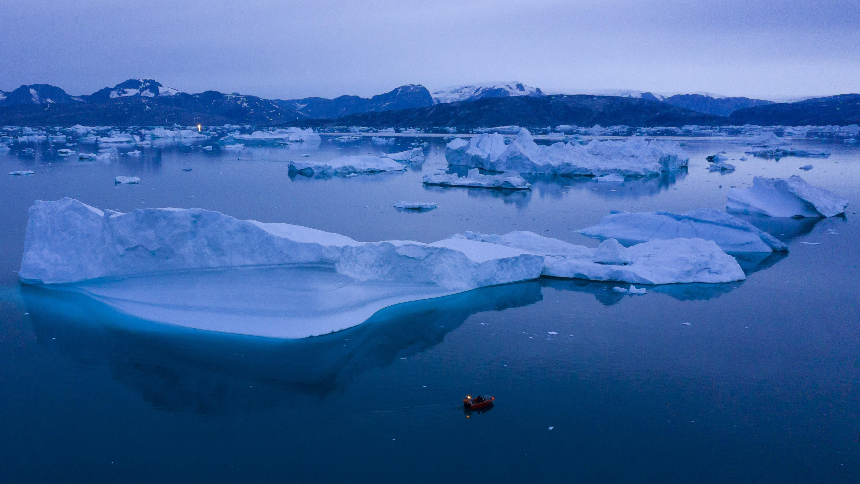 Grönlands Klimawandel in Flaschen: Schwachsinn oder sinnvoll? ARCHIV - 15.08.2019, Grönland, Kulusuk: Ein kleines Boot schwimmt inmitten eines Eisbergfeldes. Das besonders vom Klimawandel betroffene Grönland will sein Schmelzwasser einem Medienbericht zufolge zu einem Exportprodukt machen und an kommerzielle Un