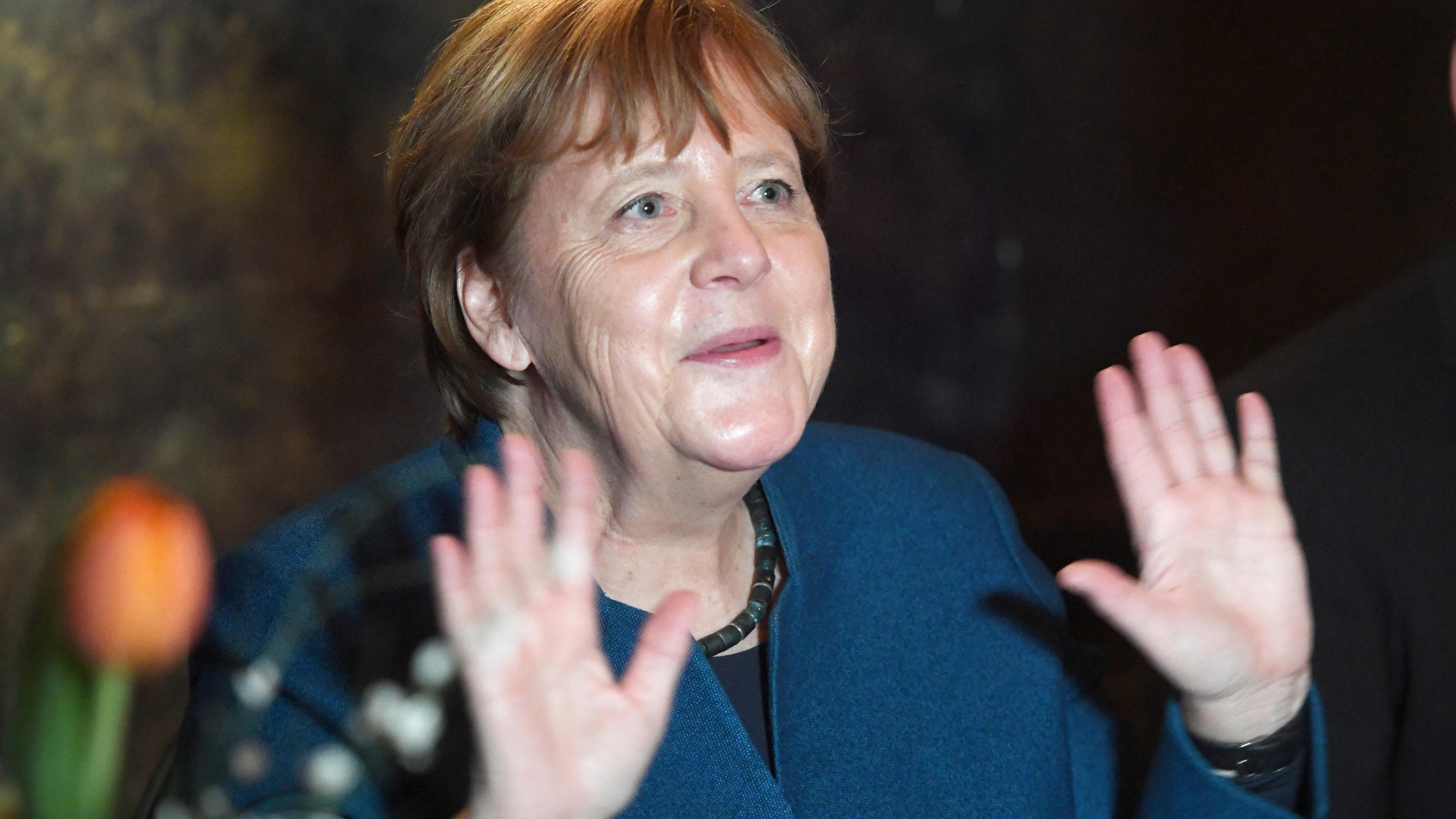 Coronavirus aus China: Chronik der bisherigen Ausbreitung - Teil 5 28.02.2020, Mecklenburg-Vorpommern, Stralsund: Bundeskanzlerin Angela Merkel (CDU) hebt auf dem Jahresempfang ihres Wahlkreises beide Hände hoch, um zu zeigen, dass sie niemandem die Hand geben möchte aufgrund einer möglichen Ansteckungsgefahr durch