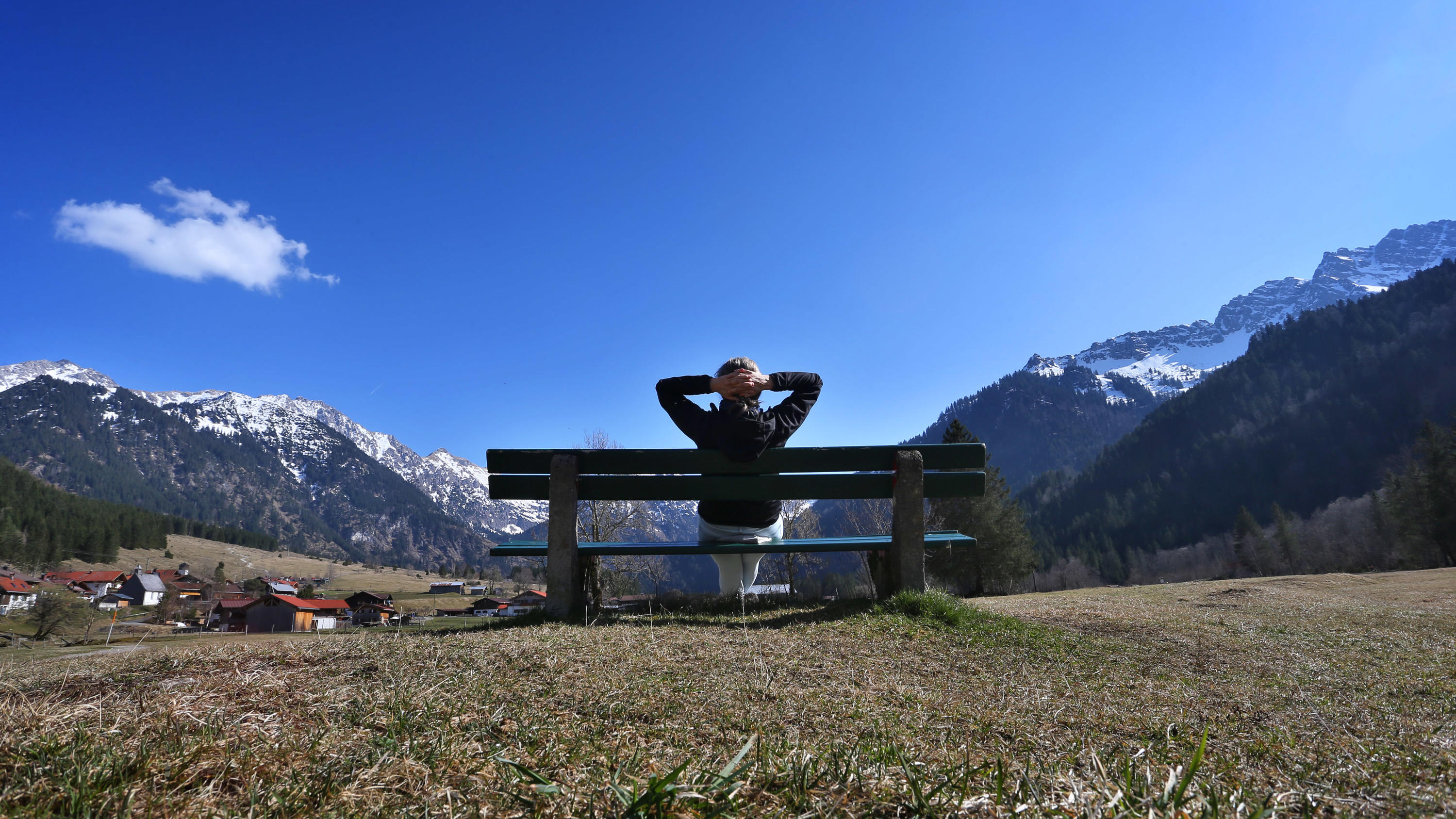 Frühlingsanfang: Fakten und Irrtümer dpatopbilder - 18.03.2020, Bayern, Bad Hindelang: Eine Wanderin genießt auf einer Bank im Hintersteiner Tal den Sonnenschein und die Aussicht auf das Panorama der Berge. Foto: Karl-Josef Hildenbrand/dpa +++ dpa-Bildfunk +++