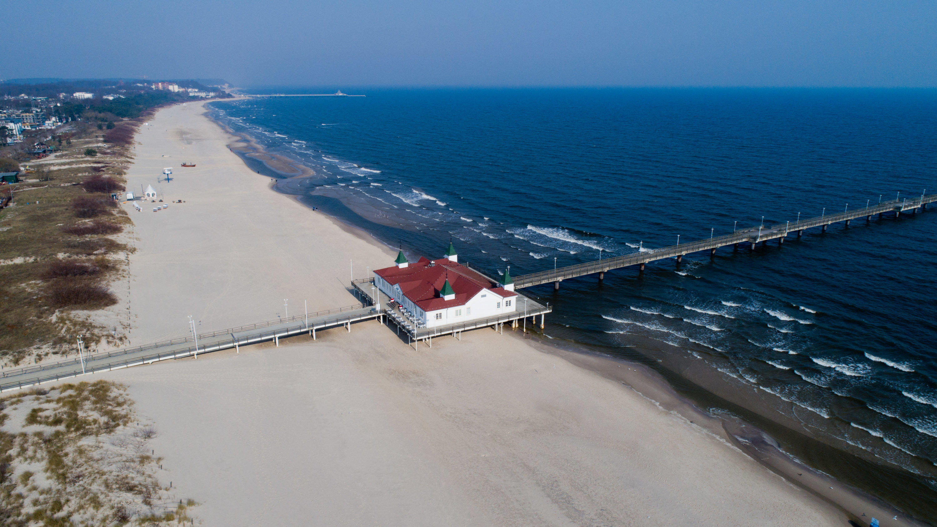 Das Coronavirus macht die Luft besser 28.03.2020, Mecklenburg-Vorpommern, Ahlbeck: Menschenleer sind der lange Strand, die Strandpromenade und die Seebrücke im Ostseebad Ahlbeck (Luftaufnahme mit einer Drohne). Um die Ausbreitung des Coronavirus zu verlangsamen, gelten derzeit Ausgangsbe