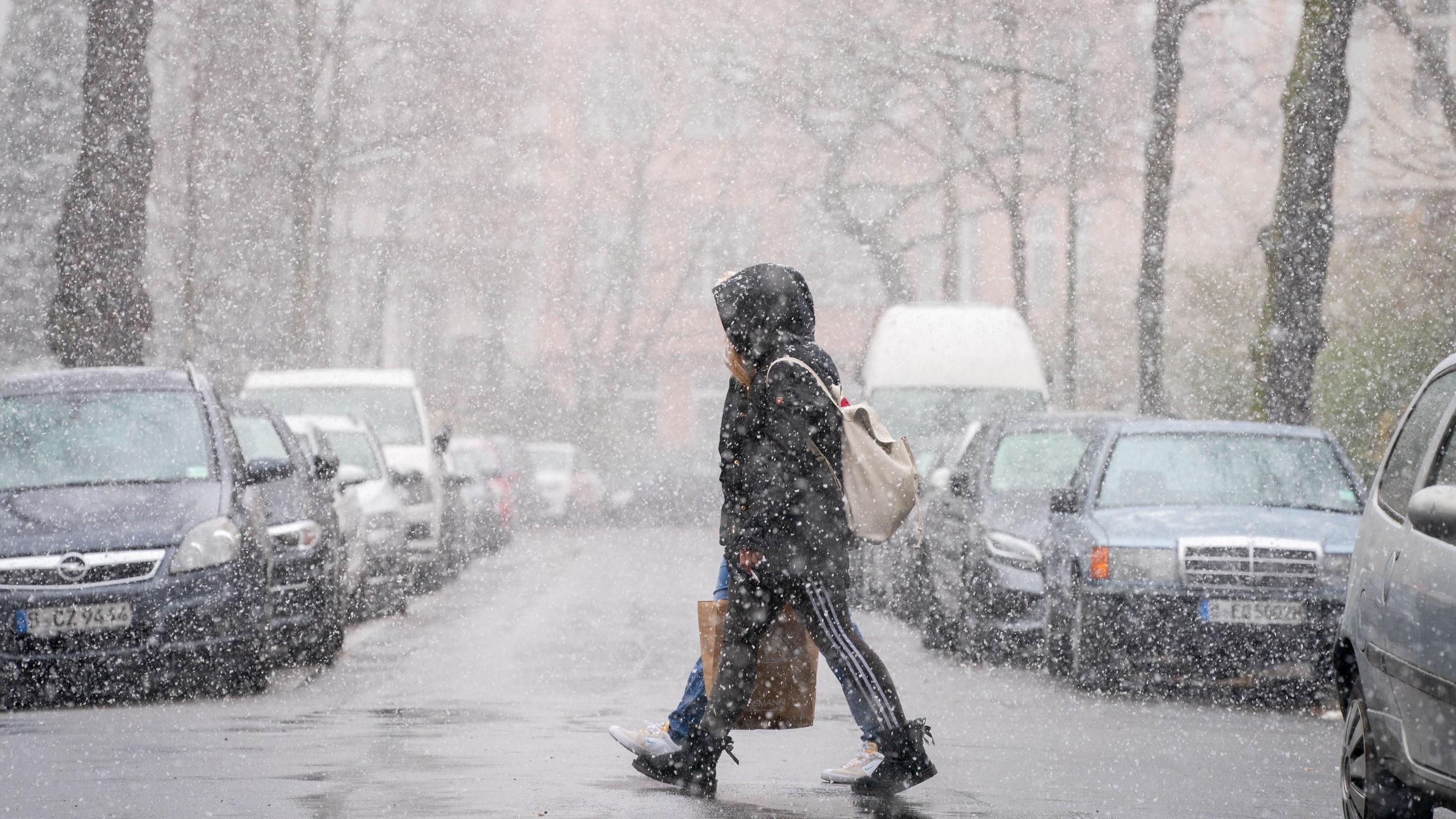 Wetterbericht zum 31.03.2020: Nach kalter Nacht und letzten Flocken geht es oft sonnig weiter 30.03.2020, Berlin: Passanten gehen bei dichtem Schneetreiben durch den Berliner Stadtteil Friedenau. Foto: Kay Nietfeld/dpa +++ dpa-Bildfunk +++