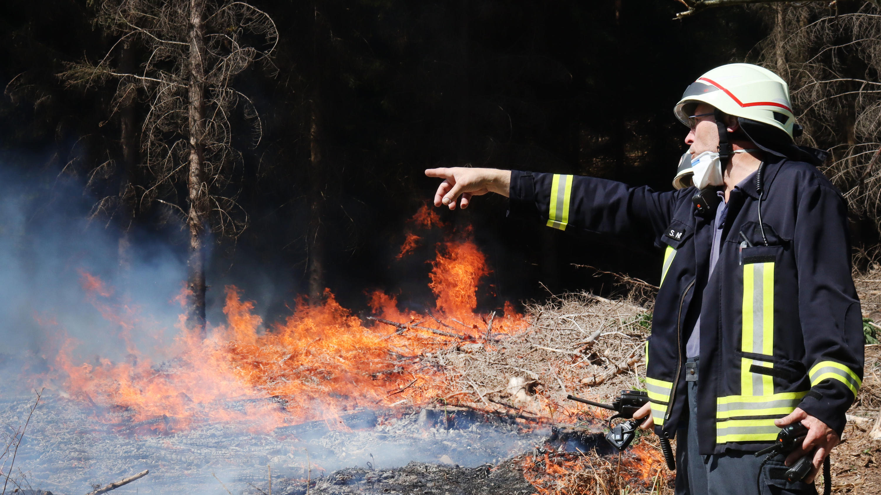 Unwetter Deutschland: Immer mehr Feuer - Wälder brennen vor allem in Nordrhein-Westfalen 20.04.2020, Nordrhein-Westfalen, Gummersbach: Ein Feuerwehrmann steht vor einem brennenden Waldstück bei Gummersbach. Foto: Berthold Stamm/dpa +++ dpa-Bildfunk +++