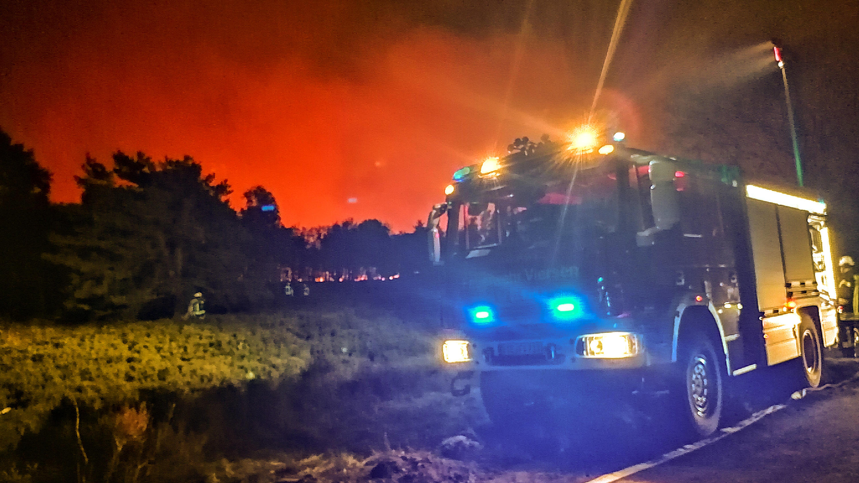 Unwetter Deutschland: Immer mehr Feuer - Wälder brennen vor allem in Nordrhein-Westfalen 20.04.2020, Nordrhein-Westfalen, Niederkrüchten: Ein Feuerwehrfahrzeug steht vor einem brennenden Waldstück. In einem niederländischen Naturschutzgebiet unmittelbar an der Grenze zu Nordrhein-Westfalen ist am Montagabend ein Großbrand ausgebrochen. A