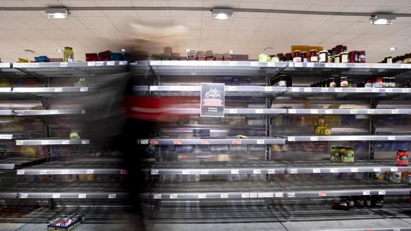 Lieferengpässe bei Lidl, Aldi, dm & Co.: Das steckt dahinter Eine Person geht in einem Supermarkt an einem fast leeren Regal vorbei.
