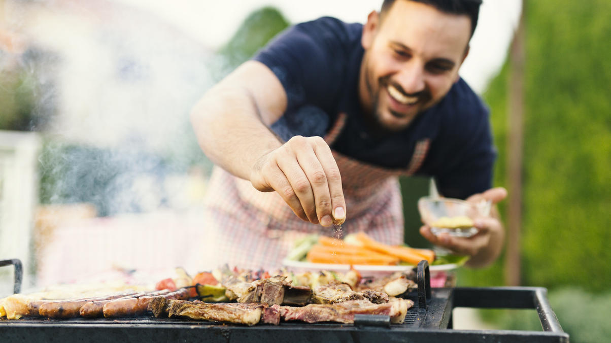 Aldi-Grill-Angebote im Check – und welche Alternativen sich lohnen Mann grillt im Garten Fleisch