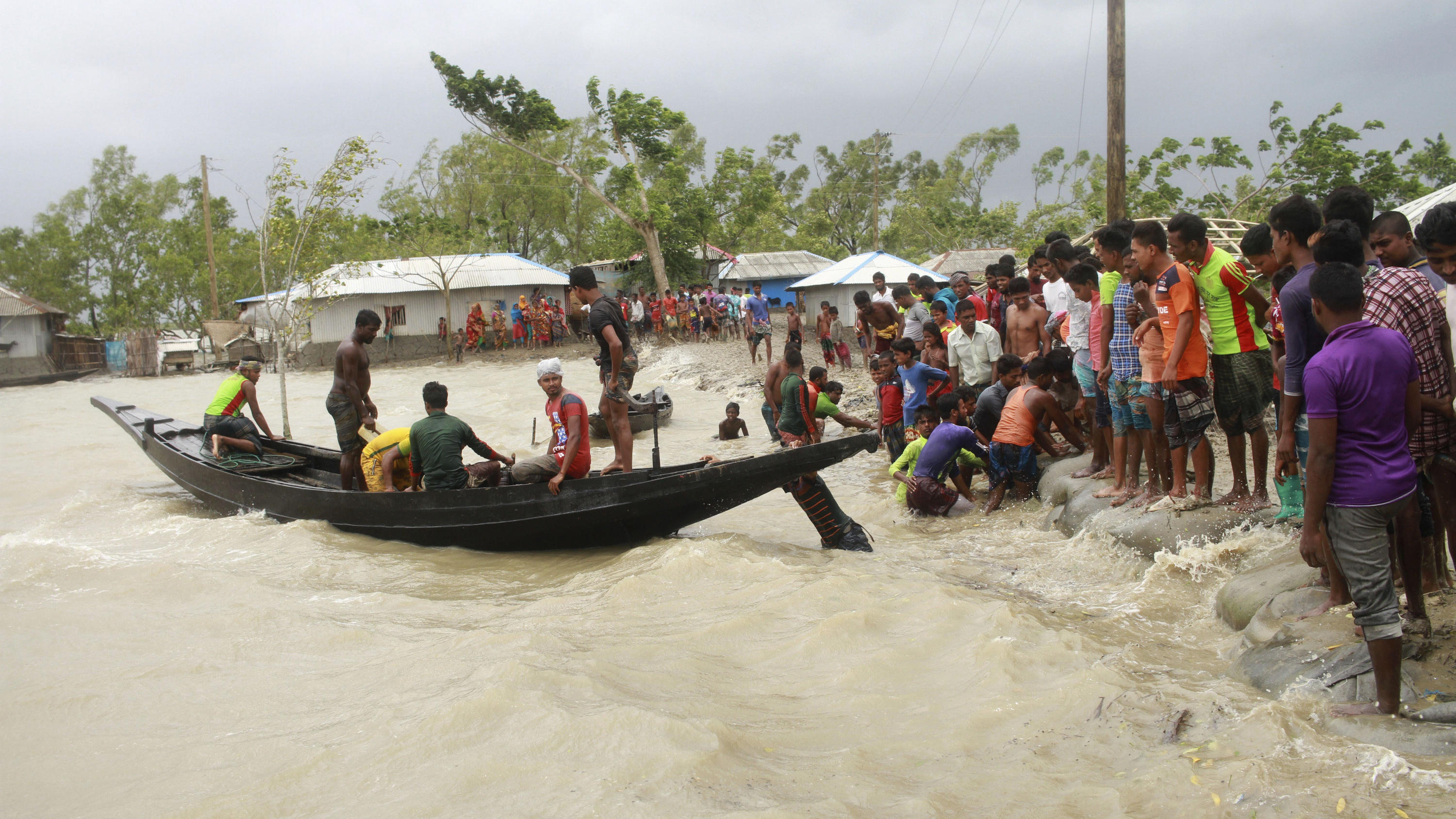 Mindestens 24 Tote bei Zyklon in Indien und Bangladesch 20.05.2020, Bangladesch, Shyamnagar: Ein Boot bringt vor der Ankunft des Zyklons «Amphan» Menschen ans Land, während Einheimische einen Damm überprüfen. Der Wirbelsturm hat in Indien und Bangladesch über zehn Menschen das Leben gekostet. Sie starben