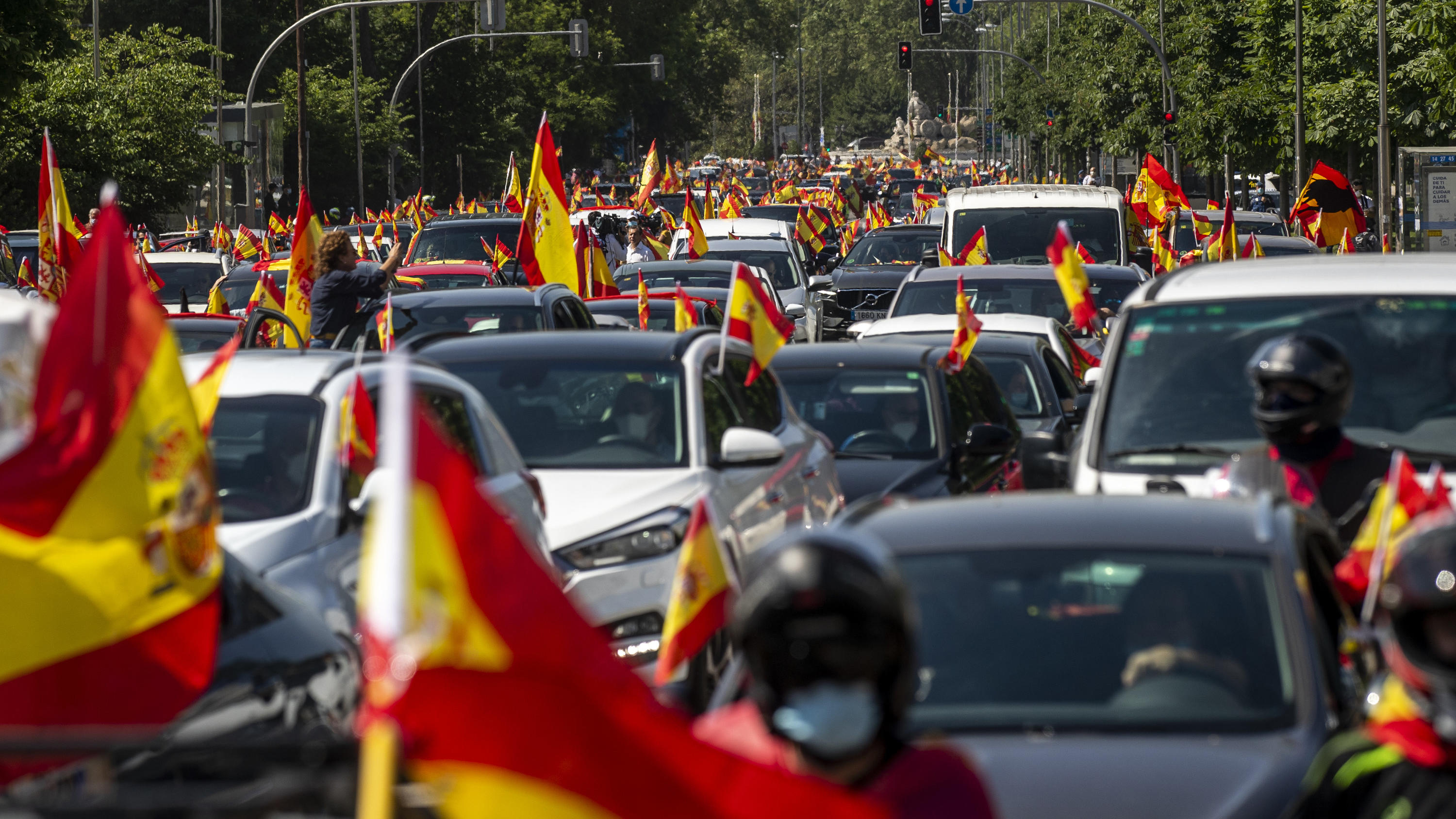 Spanien lässt Touristen erst ab Juli ins Land 23.05.2020, Spanien, Madrid: Anhänger der rechtspopulistischen Partei Vox schwenken bei einer Demonstration die Nationalflagge von Spanien. Tausende haben bei Kundgebungen in ganz Spanien gegen die Anti-Corona-Maßnahmen den Rücktritt des sozialistisc