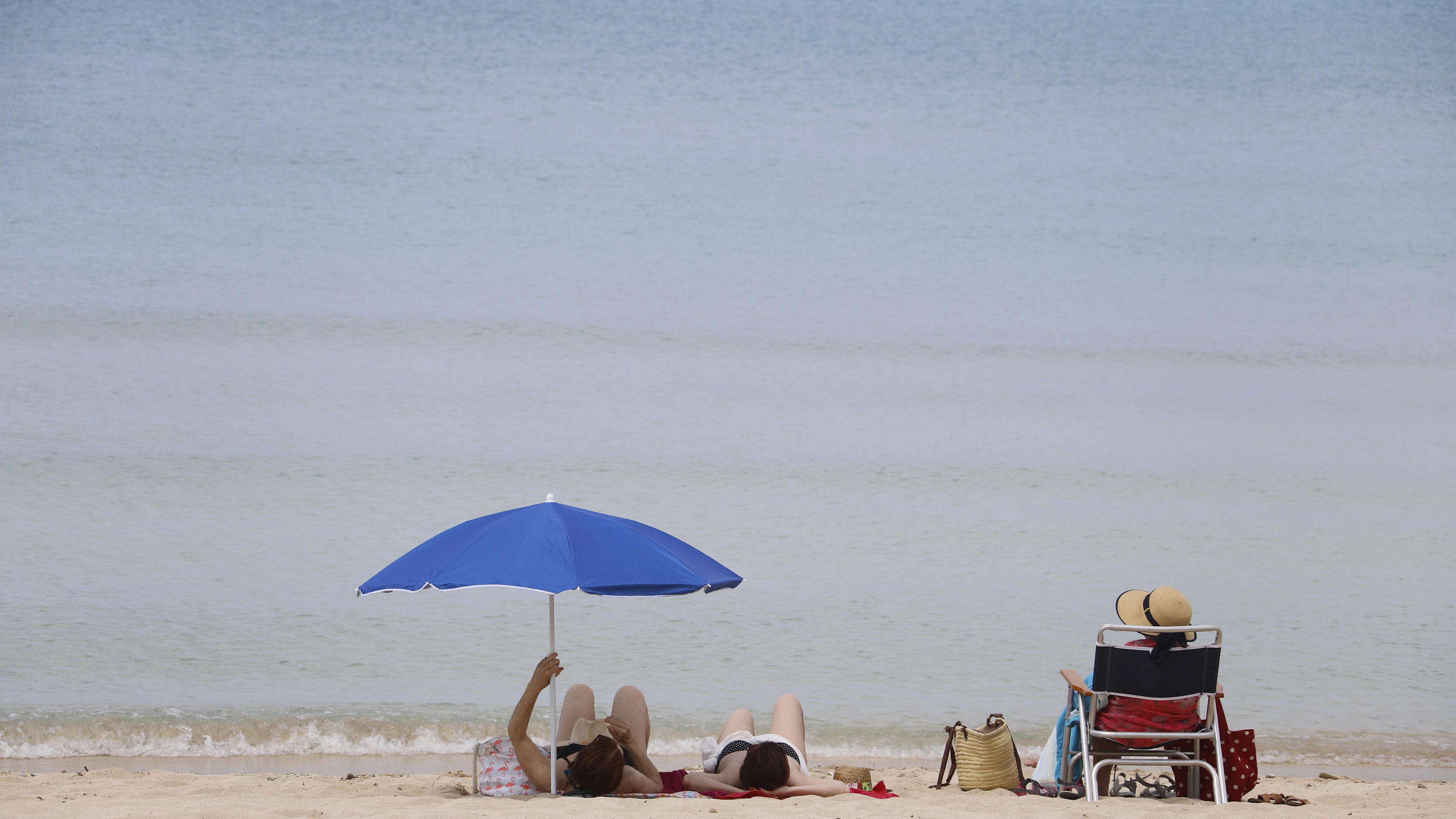 Bundesregierung will Reisewarnung für 31 Länder aufheben 25.05.2020, Spanien, Palma de Mallorca: Menschen sonnen sich am Strand von Arenal. Nach einer mehr als zweimonatigen Zwangsschließung wegen der Corona-Pandemie haben die Urlaubsinsel und viele andere Regionen Spaniens am Montag ihre Strände wieder ge