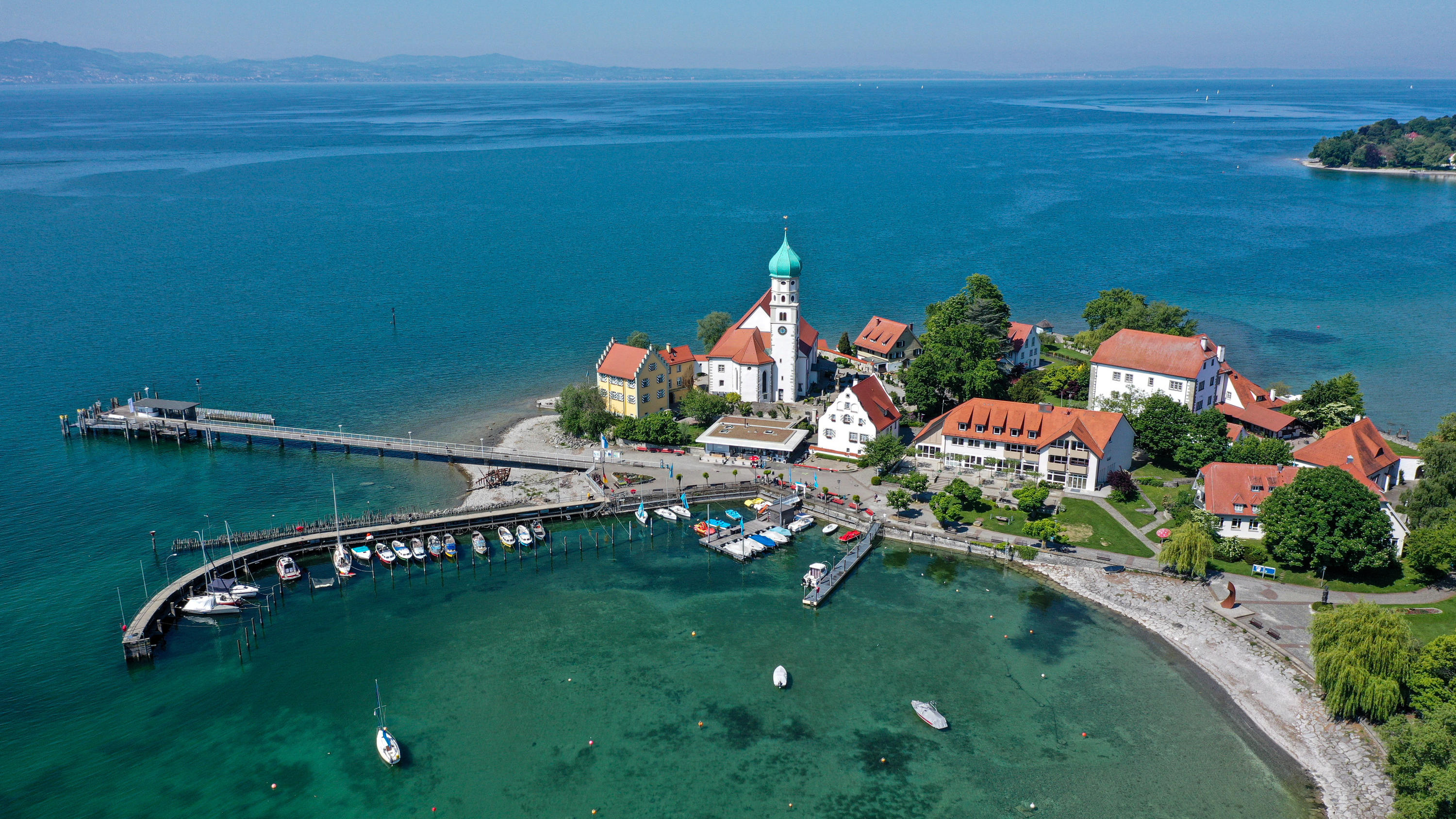 Reisewetter an Pfingsten: Schönes Ausflugswetter 18.05.2020, Bayern, Wasserburg Am Bodensee: Nur wenige Menschen tummeln sich rund um die Kirche und den Molesteg von Wasserburg am Bodensee (Luftaufnahme mit Drohne). Im Hintergrund sind die Schweizer Alpen zu sehen. Foto: Felix Kästle/dpa +++ dpa-Bi