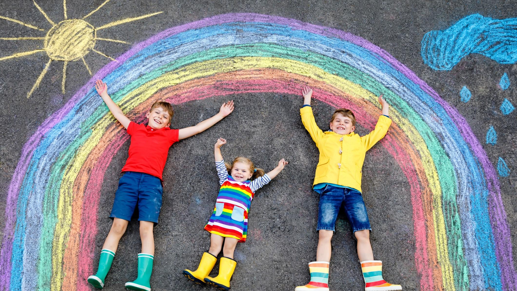 Wetterbericht für den 07.06.2020: Perfektes Regenbogenwetter three little children, two school kids boys and toddler girl having fun with with rainbow picture drawing with colorful chalks on asphalt. Siblings in rubber boots painting on ground playing together