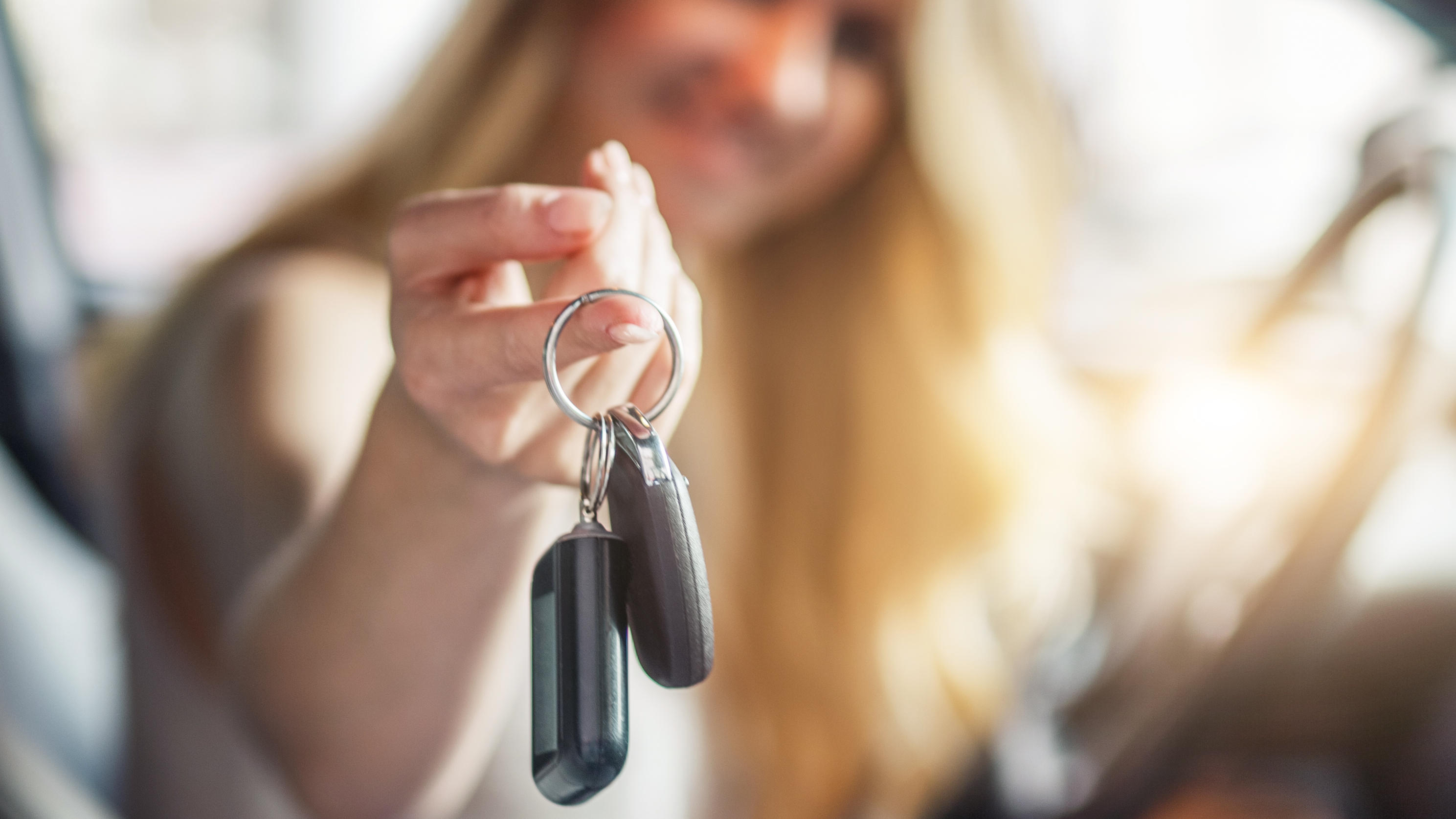 Brütende Hitze im Auto? Der Schlüssel-Trick bringt schnelle Abkühlung Frau sitzt im Auto und hält Autoschlüssel in der Hand