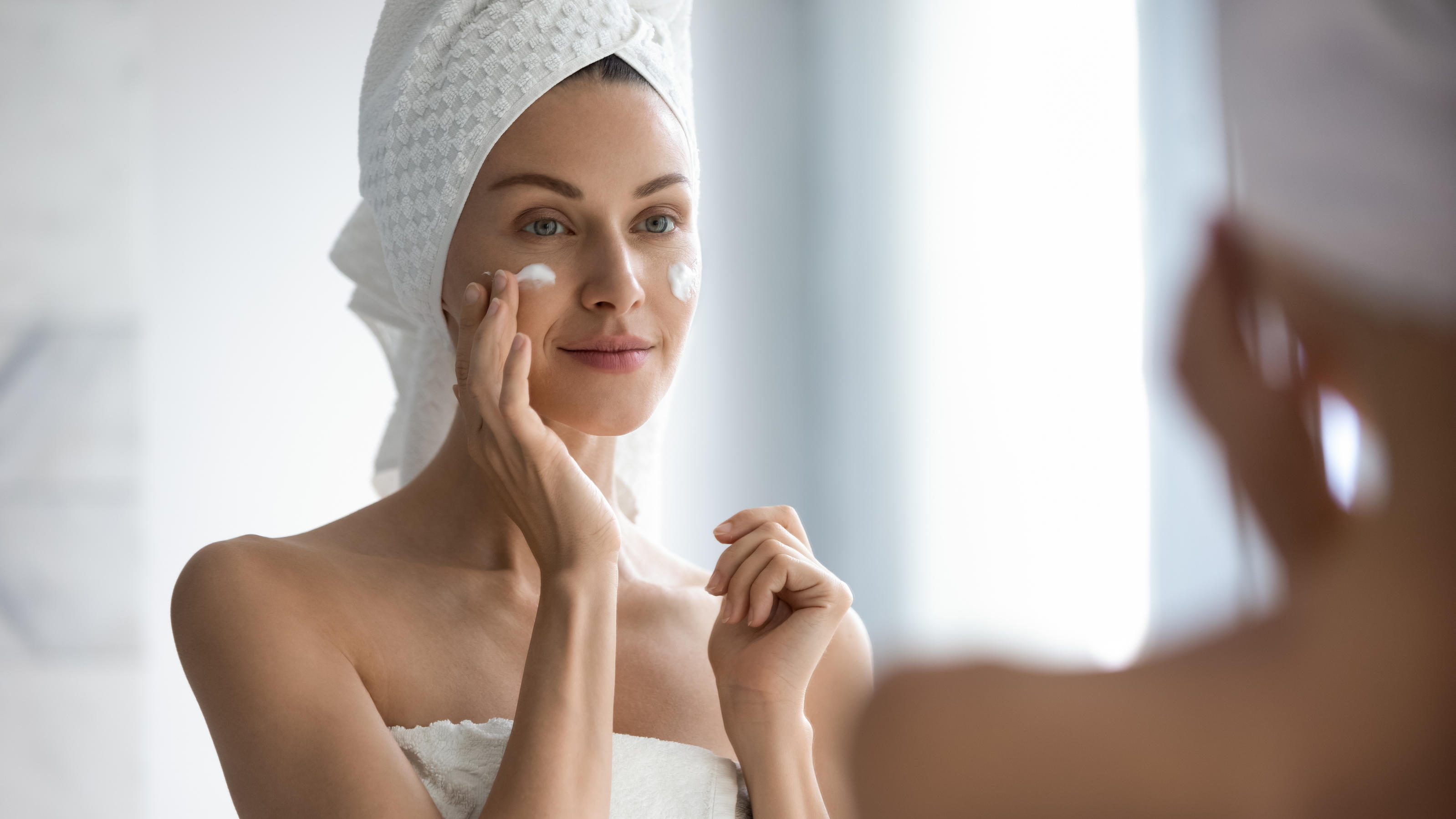 Creme selber machen: Rezepte für Rosen- und Aloe-Vera-Creme Frau cremt ihr Gesicht ein