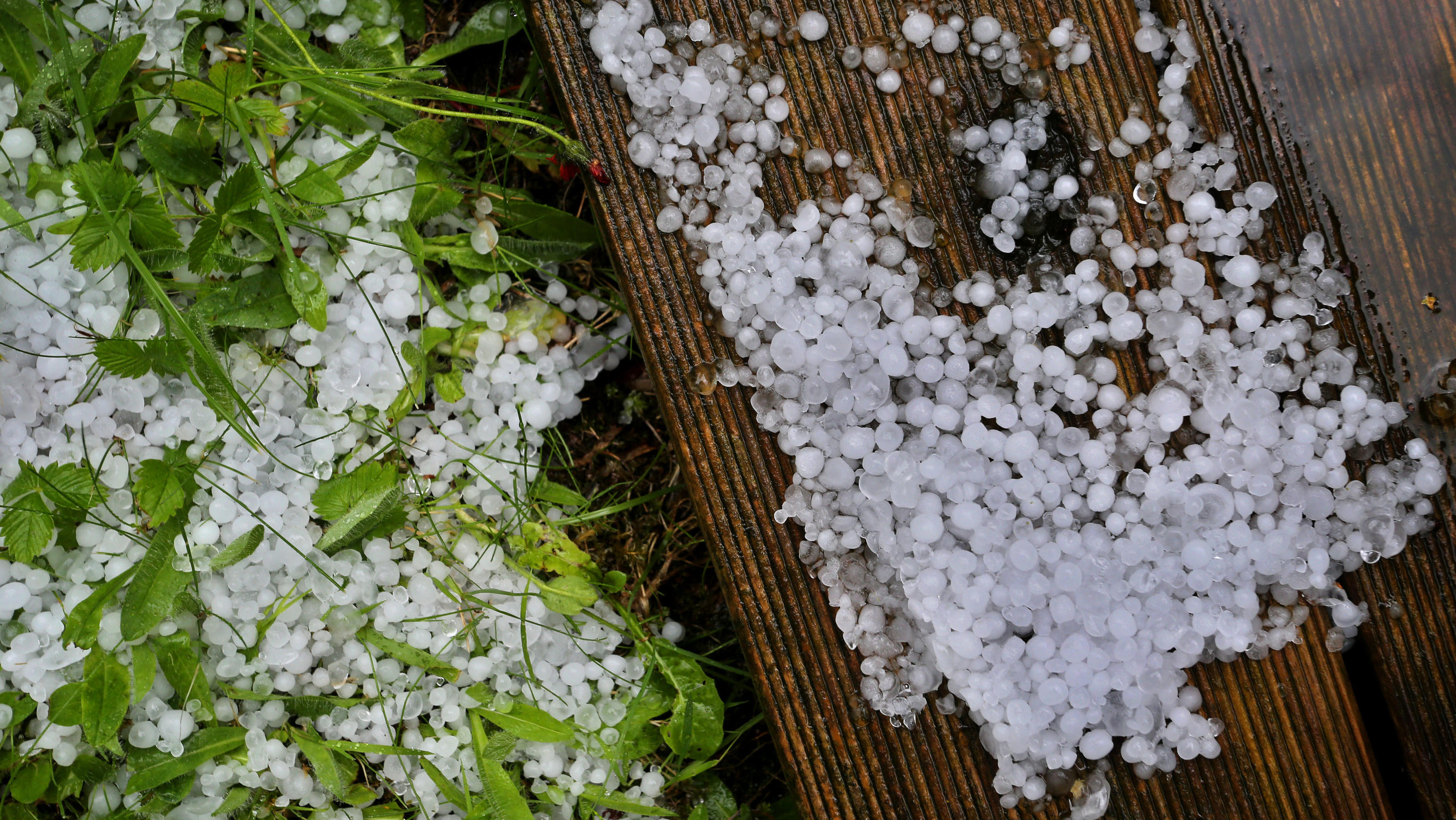Wetter-Rückblick Juni 2020: Zu warm und zu nass – ein wechselhafter Start in den Sommer 02.07.2020, Bayern, Kaufbeuren: Hagelkörner liegen in einem Garten auf einer Holzterrasse und dem Rasen. Foto: Karl-Josef Hildenbrand/dpa +++ dpa-Bildfunk +++