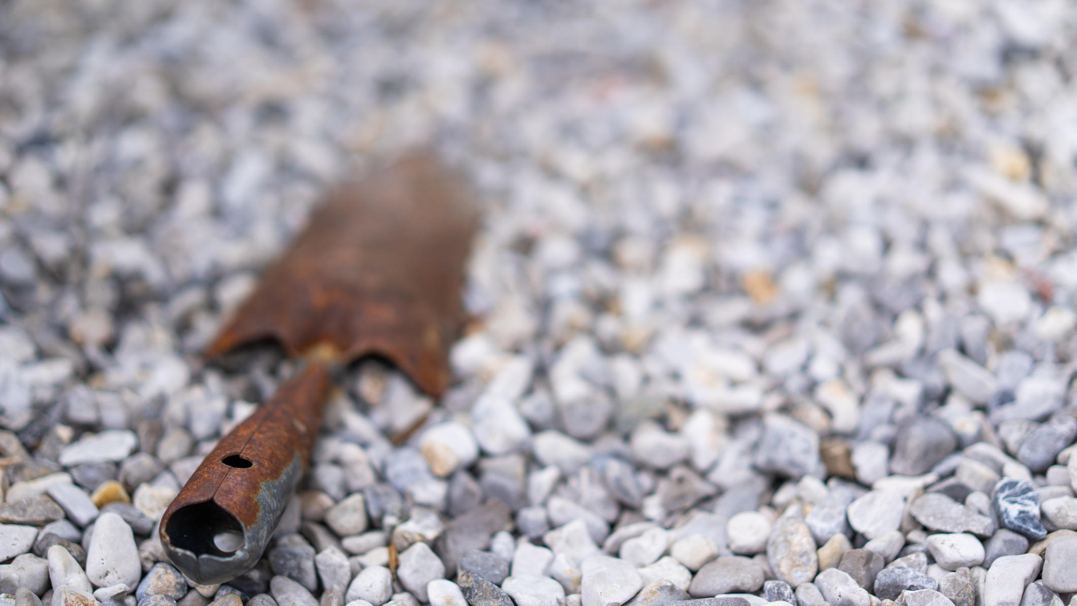 Schottergarten-Verbot: richtig oder falsch? rusty garden shovel in gravel with place for text, shallow focus on foreground, background blurred