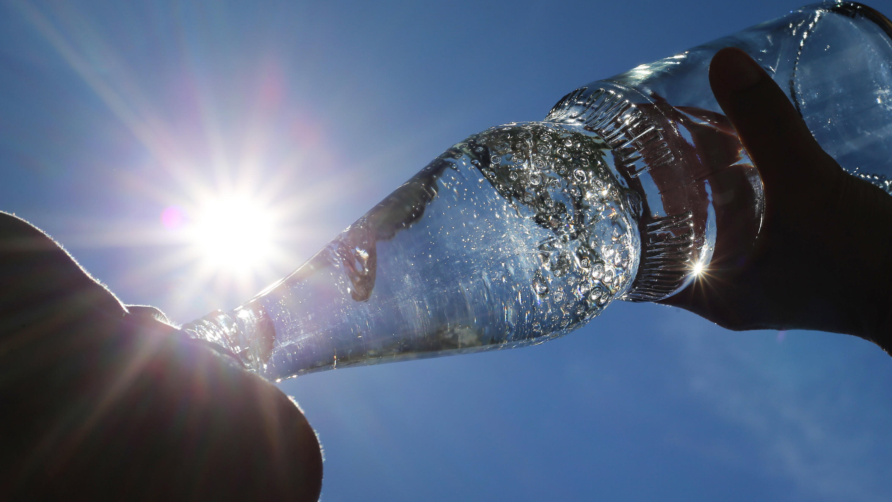 Bier, Wein & Co: Was darf ins Gefrierfach – und wie lang? ARCHIV - 24.06.2019, Bayern, Kempten: Eine Frau trinkt im Sonnenschein aus einer Flasche sprudelndes Mineralwasser. (zu dpa:
