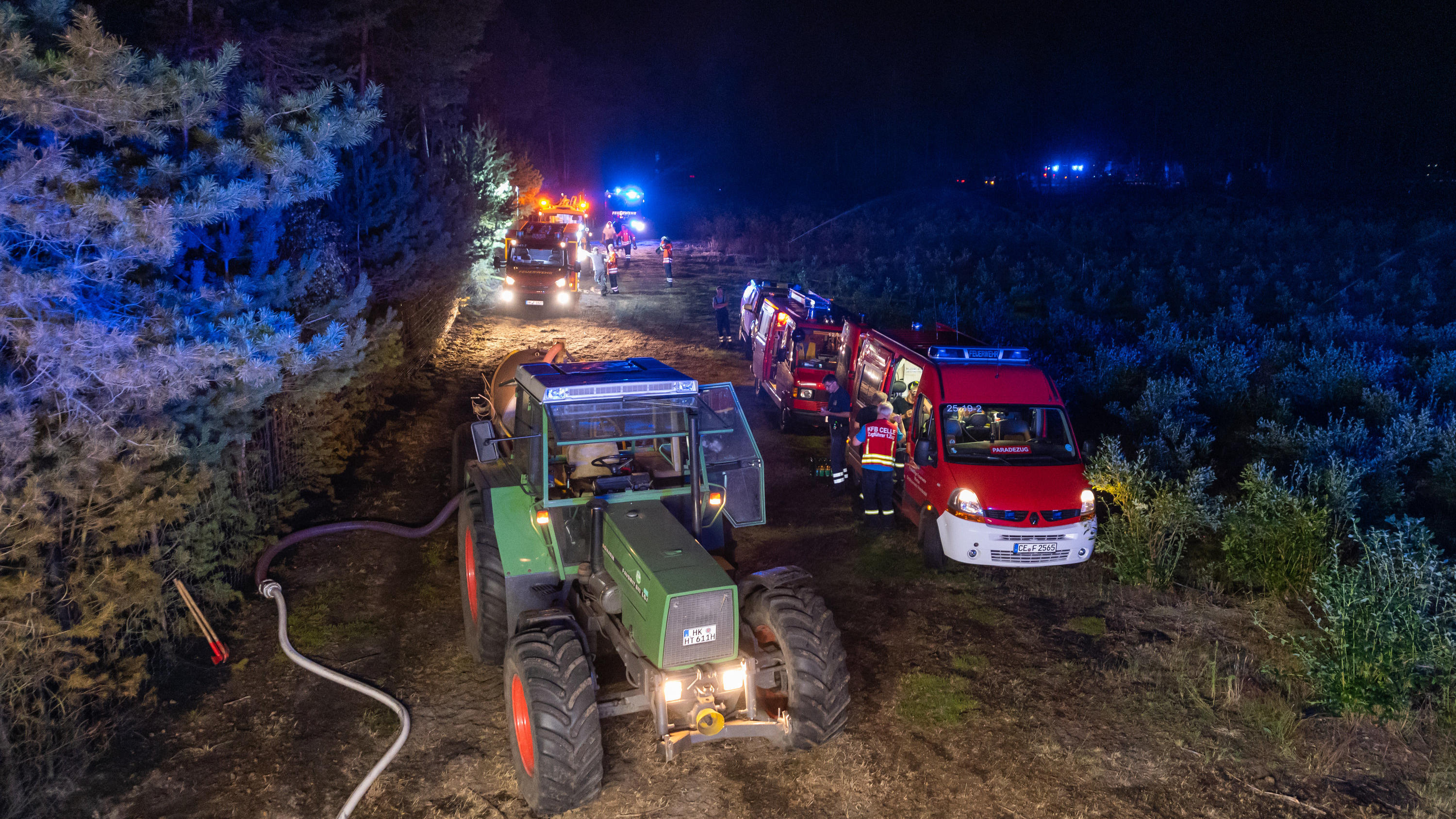 Reifenpanne an der A7 führt zu Waldbrand im Heidekreis 12.08.2020, Niedersachsen, Essel: Ein Trekker und Einsatzfahrzeuge der Feuerwehr stehen für Nachlöscharbeiten an einem Waldstück. Wegen eines großflächigen Brandes im Heidekreis ist das Wochenendgebiet Esseler Wald am Mittwochabend nach Polizeiangabe