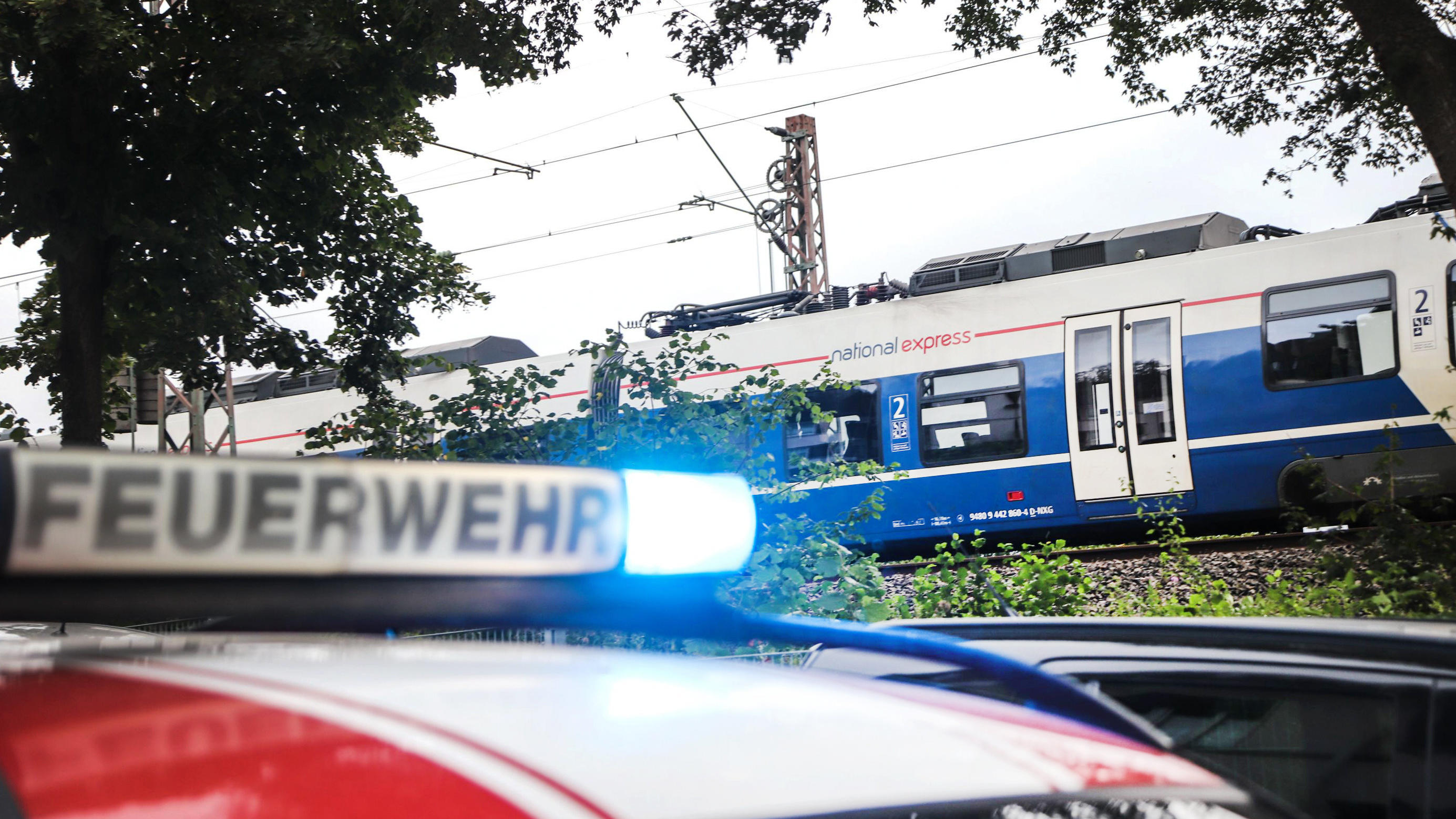 Sturm Kirsten: Das war der Live-Ticker Ein Fahrzeug der Feuerwehr steht vor einem Nahverkehrszug, der wegen Sturmschäden an der Oberleitung zum Stehen gekommen ist.