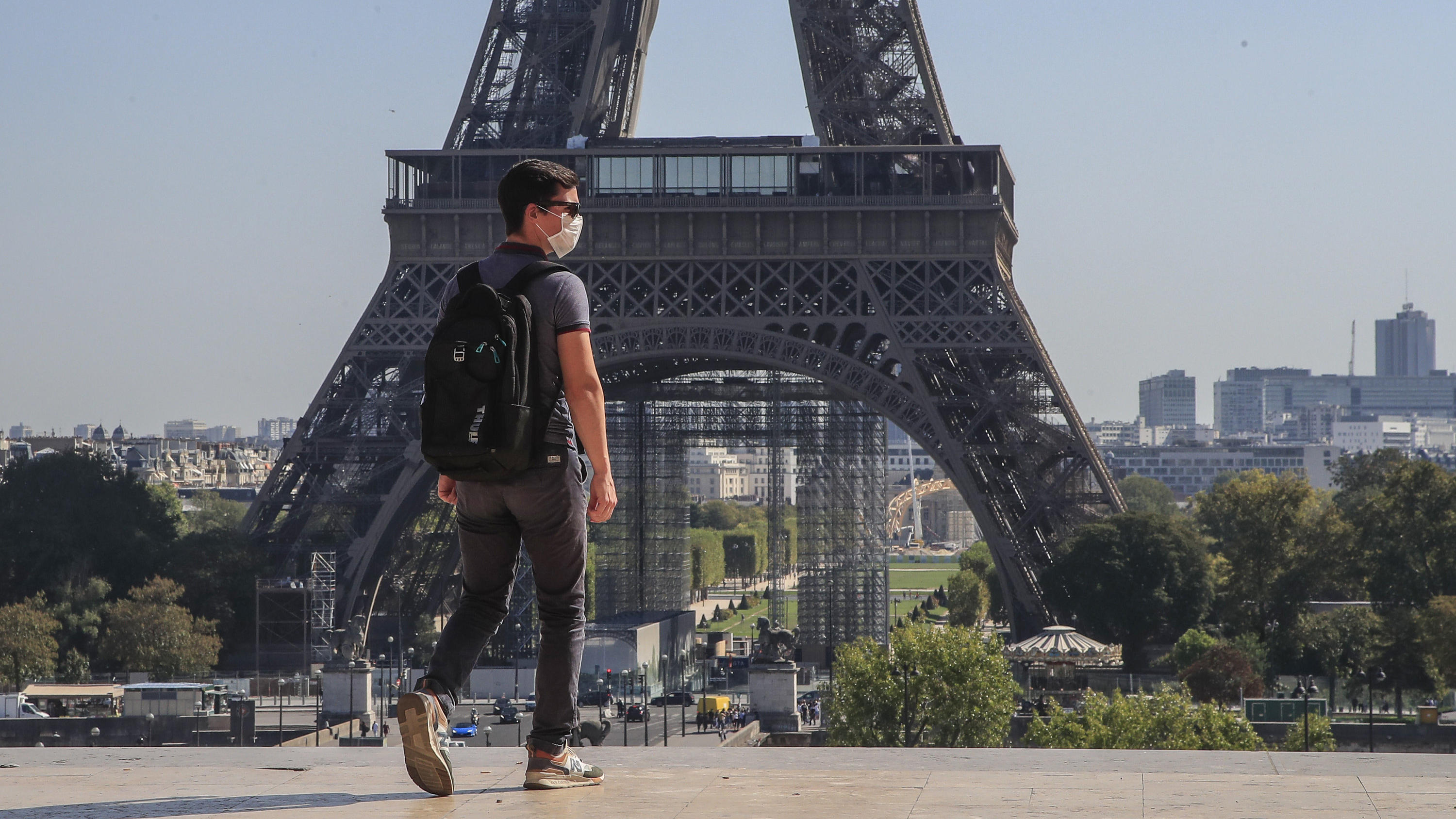 Was jetzt in welchem europäischen Land gilt Frankreich, Paris: Ein Passant geht mit Mundschutzmaske über den Place du Trocadéro, während im Hintergrund ein Teil des Eiffelturms zu sehen ist