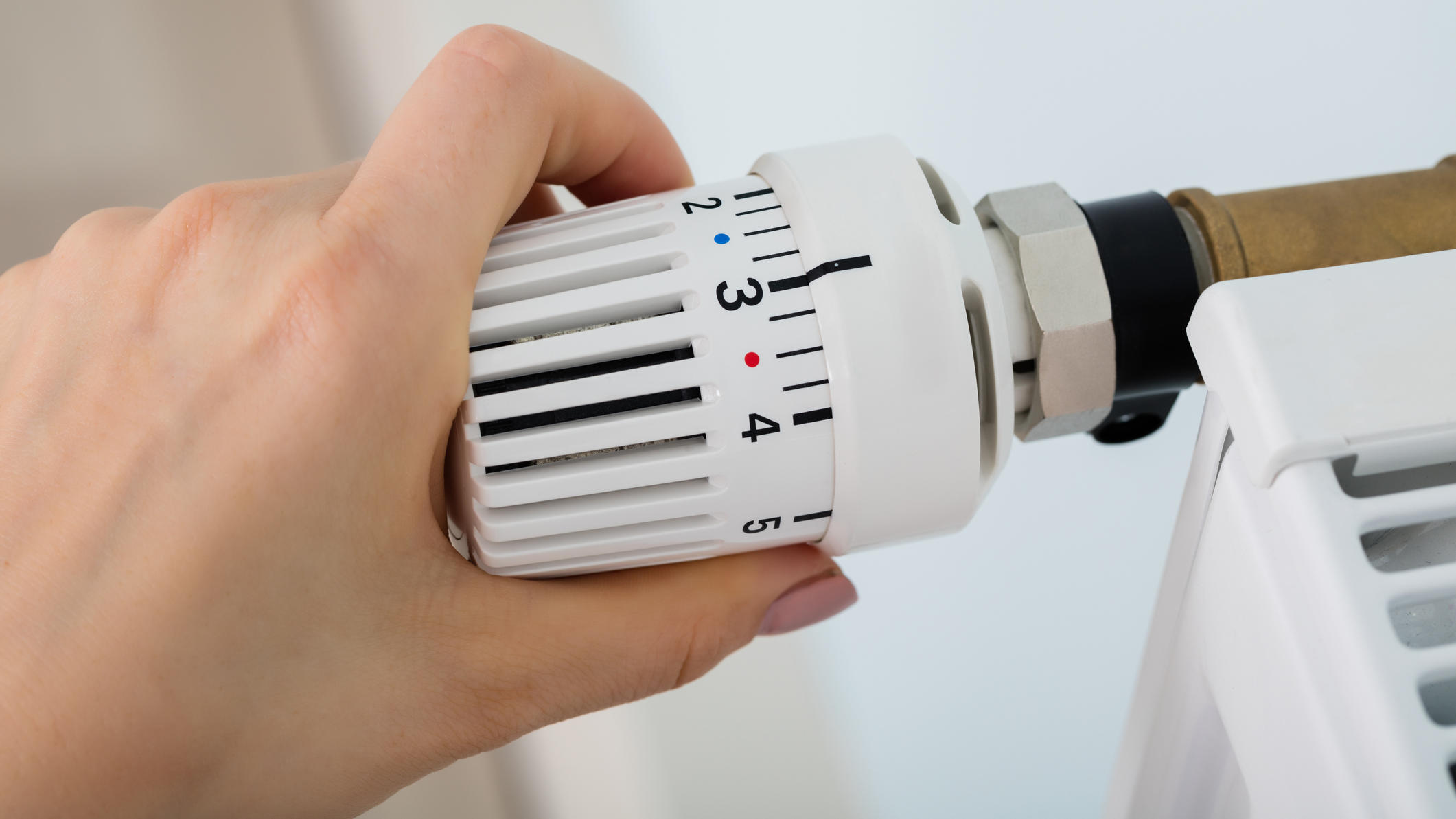 Richtig heizen: Dafür stehen die Zahlen 1 bis 5 auf dem Thermostat wirklich Frau dreht am Thermostat der Heizung