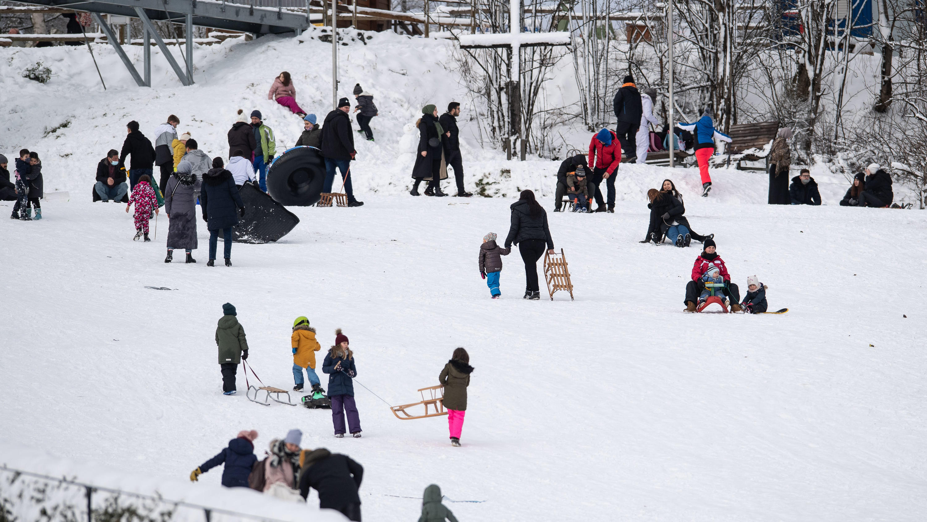 Ansturm auf Deutschlands Skigebiete - Polizei appelliert: 01.01.2021, Nordrhein-Westfalen, Winterberg: Ausflügler tummeln sich mit ihren Schlitten auf einem verschneiten Hang. Die Stadt Winterberg bittet wegen der Corona-Pandemie auf Besuche in dem Wintersportort und an den Pisten im Sauerland zu verzichten