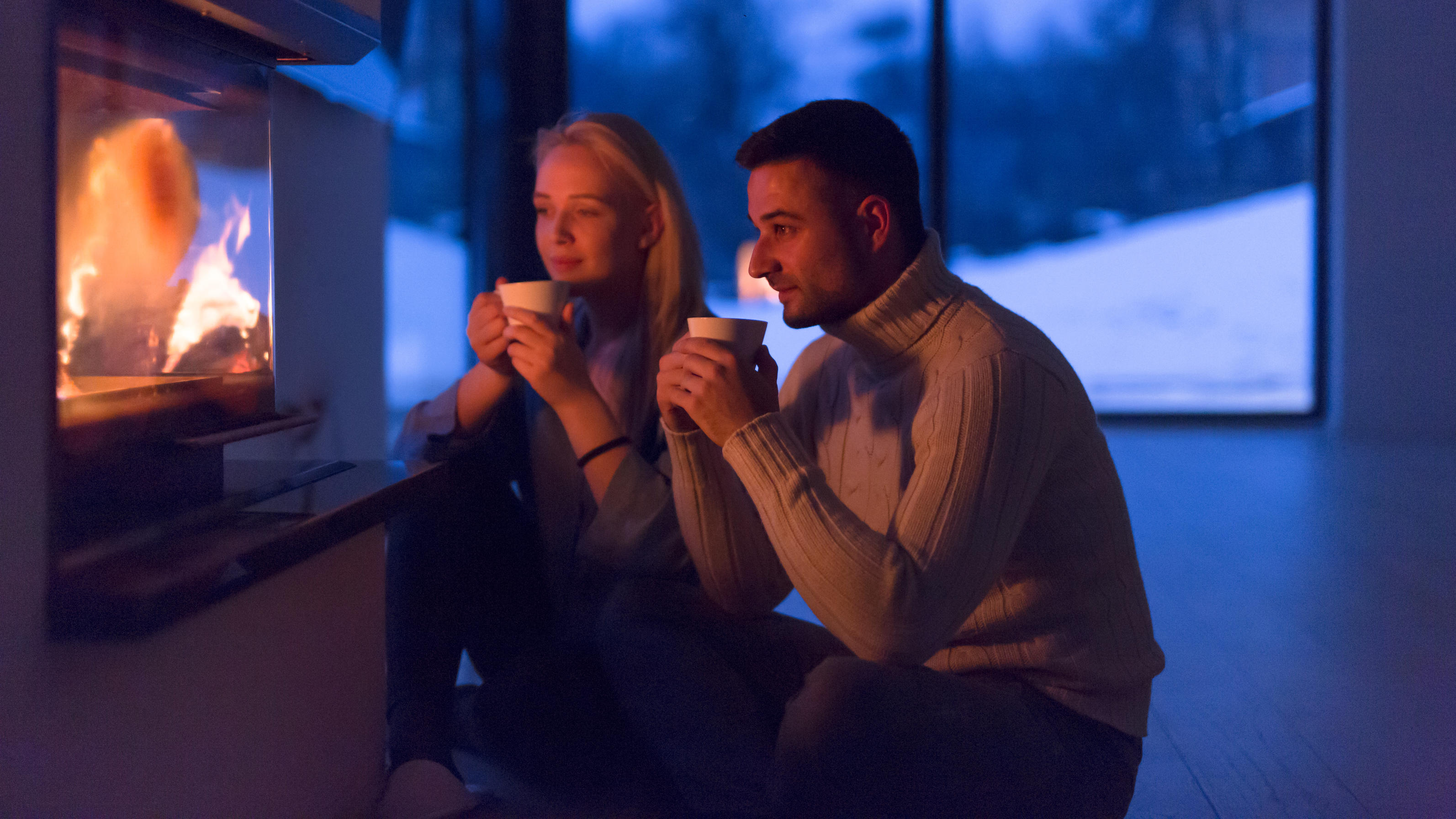 Wetter am Wochenende mit eiskalten Temperaturen Young romantic couple sitting on the floor in front of fireplace,talking and drinking tea on cold winter night at home,model released, Symbolfoto PUBLICATIONxINxGERxSUIxAUTxONLY ING32193154349