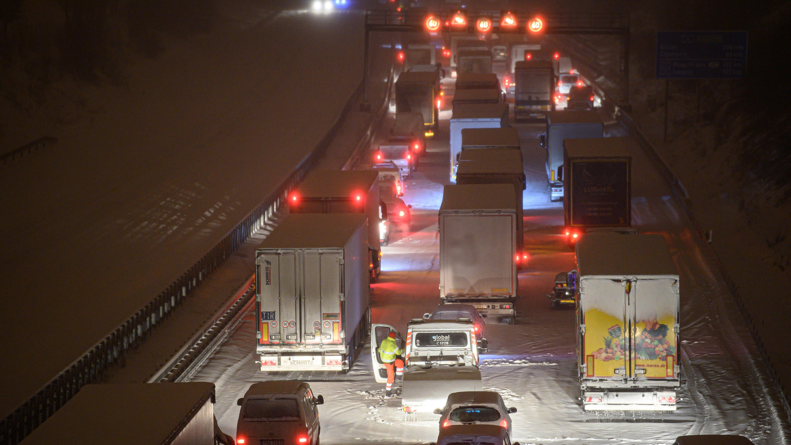 Zwei Tote im Schnee entdeckt ++++ Dach von Holzfachhandel eingestürzt 08.02.2021, Sachsen, Dresden: Autos und Lastwagen stehen am frühen Morgen bei Schneefall auf der verschneiten Autobahn 4 bei Dresden im Stau, während ein Mann neben seinem Auto steht. Foto: Robert Michael/dpa-Zentralbild/dpa +++ dpa-Bildfunk +++