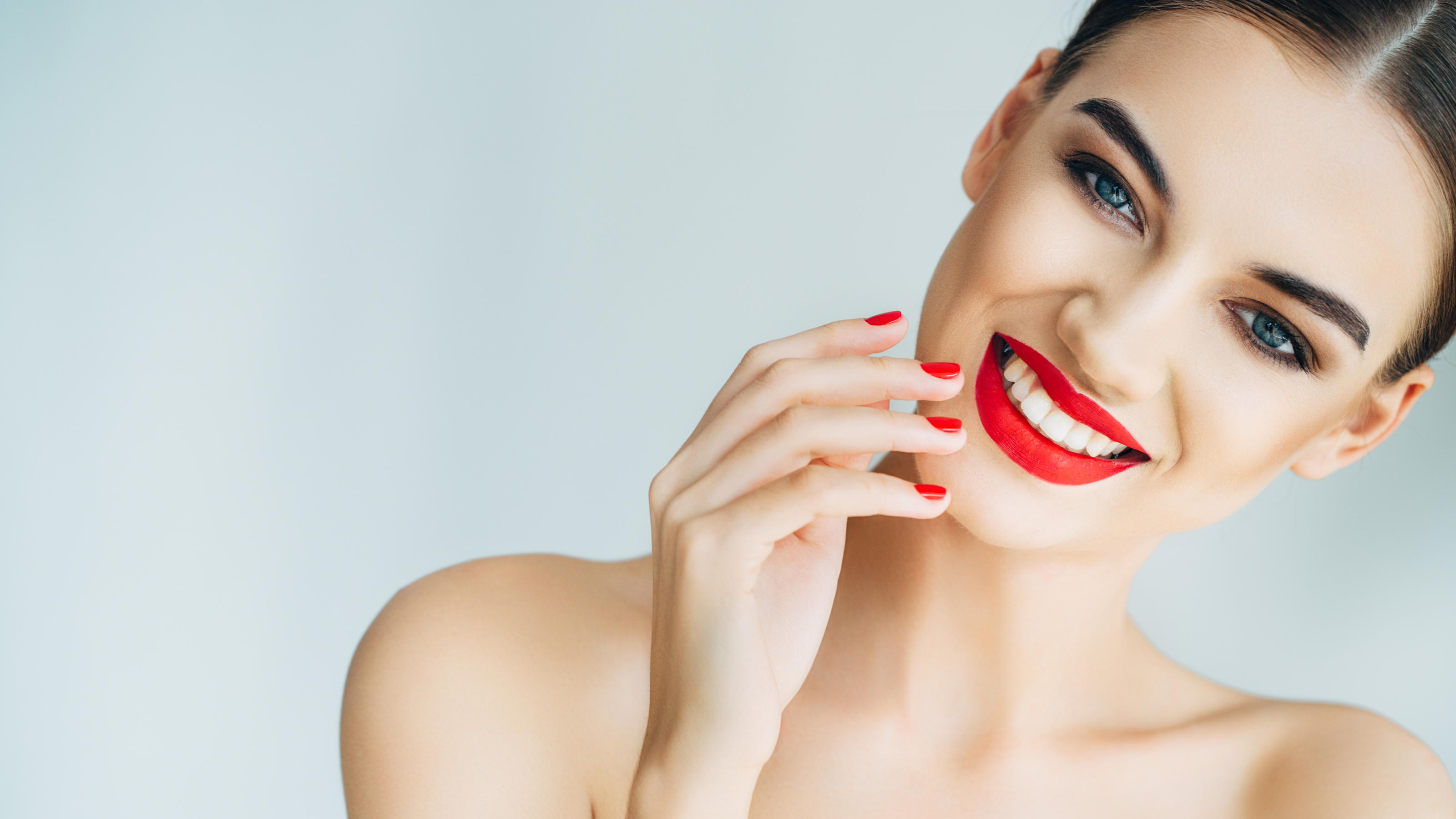 Liquid Lipsticks: Darum ist der Flüssig-Lippenstift so angesagt Eine lächelnde Frau, die roten Lippenstift trägt.