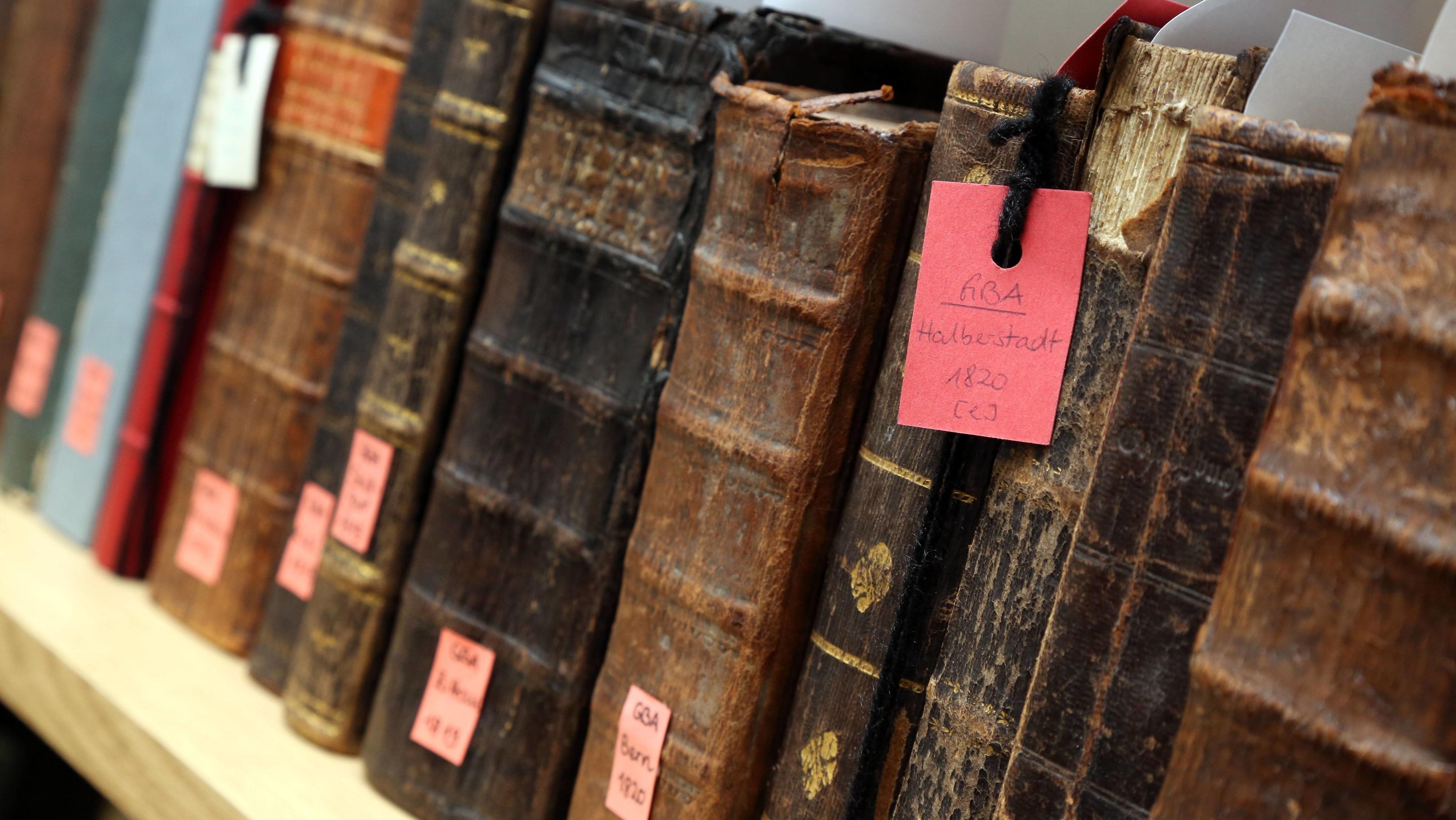Was bedeutet das Bild bei Google heute? Alles rund um Johannes Gutenberg In einem Regal, vermutlich in einer Bibliothek, stehen nebeneinander gereiht einige sehr alte Bücher.